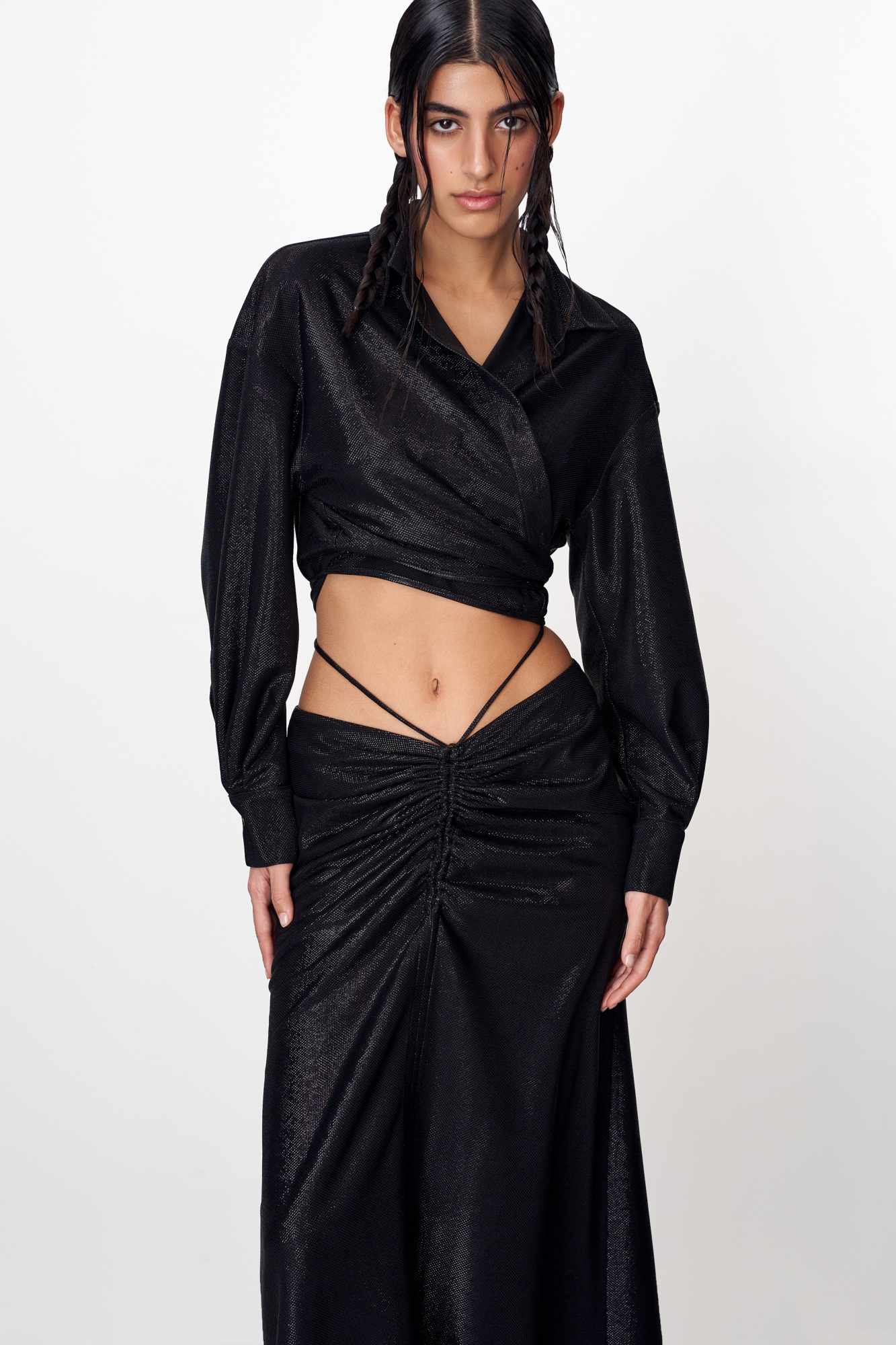 Металлизированный комплект. Укороченная рубашка с длинными рукавами. Силуэт модели прямой, воротник классический. Рубашка с кулиской по нижнему краю и декоративным разрезом на спинке. Юбка длины макси со сборкой спереди. Декорирована завязками на талии.