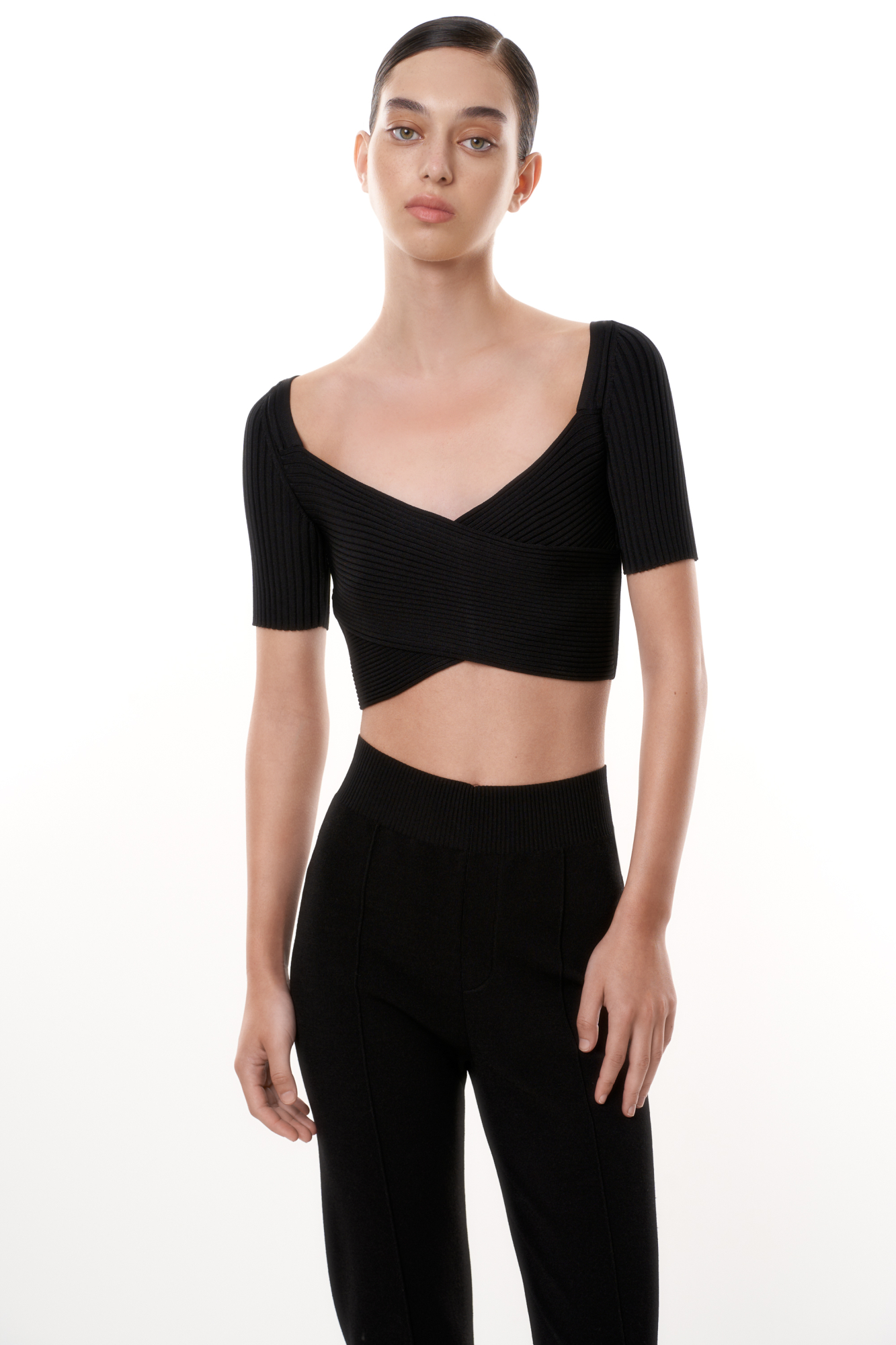 Короткий трикотажный топ из вискозы. Модель приталенного силуэта, с коротким рукавом, глубоким вырезом и скрещенным лифом. Изделие выполнено в рубчик.