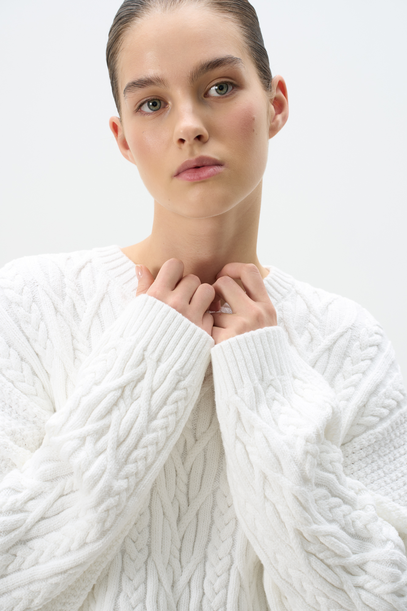 Трикотажный джемпер из вискозы и хлопка. Модель свободного силуэта со спущенной линией плеч, объемными рукавами и круглым вырезом горловины. Изделие декорировано фактурной вязкой в виде кос разной толщины. Края выполнены в рубчик.