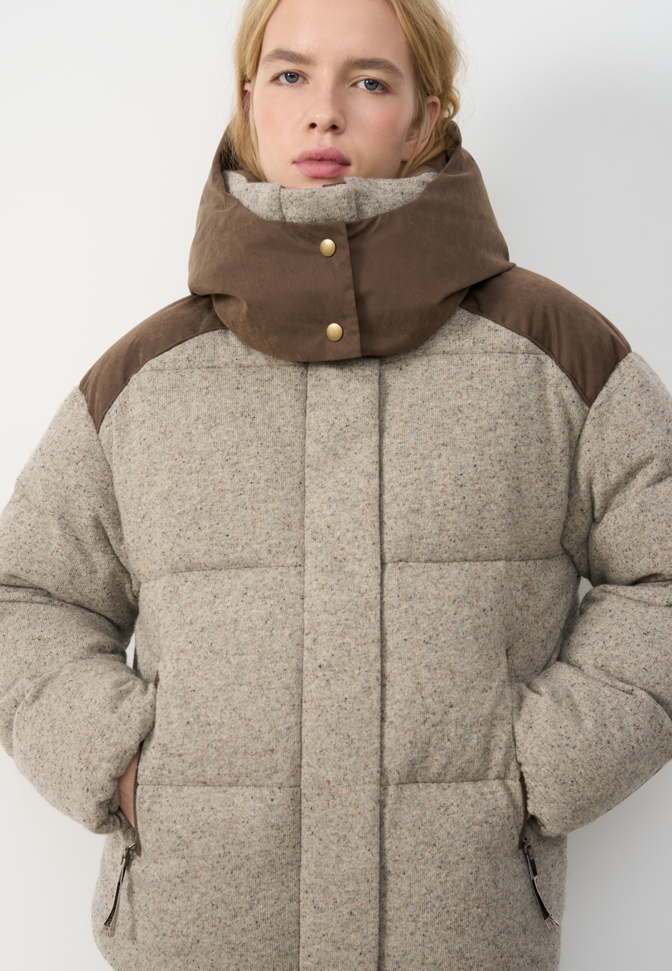 Трикотажный пуховик из шерсти с добавлением вискозы и шелка. Модель свободного силуэта с воротником-стойкой, капюшоном и карманами на молниях. Застежка на молнию под планкой с кнопками.