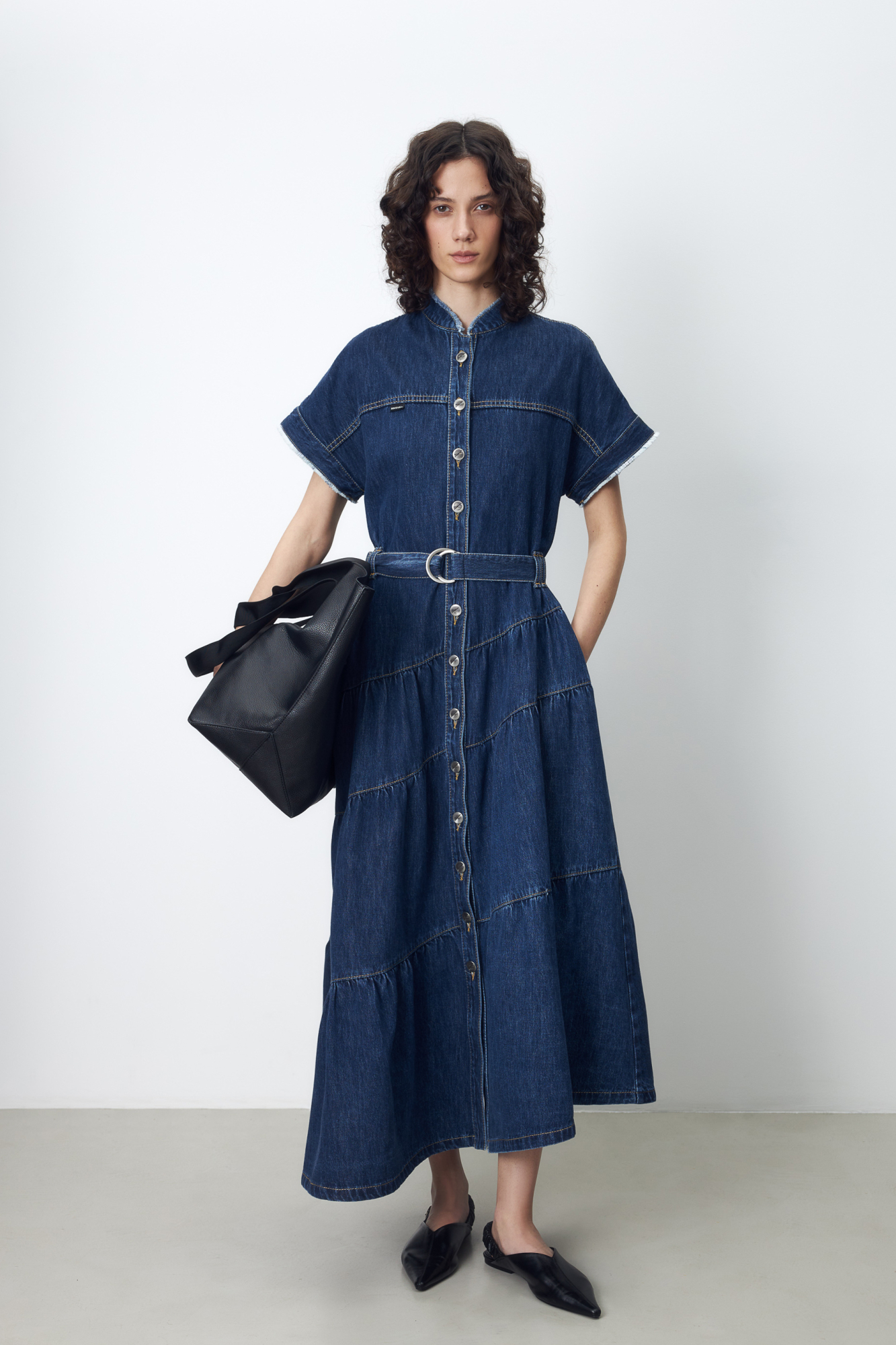 Джинсовое платье-рубашка с асимметричным низом и поясом в тон. Застёжка на пуговицы обеспечит удобство надевания и регулировку глубины выреза.