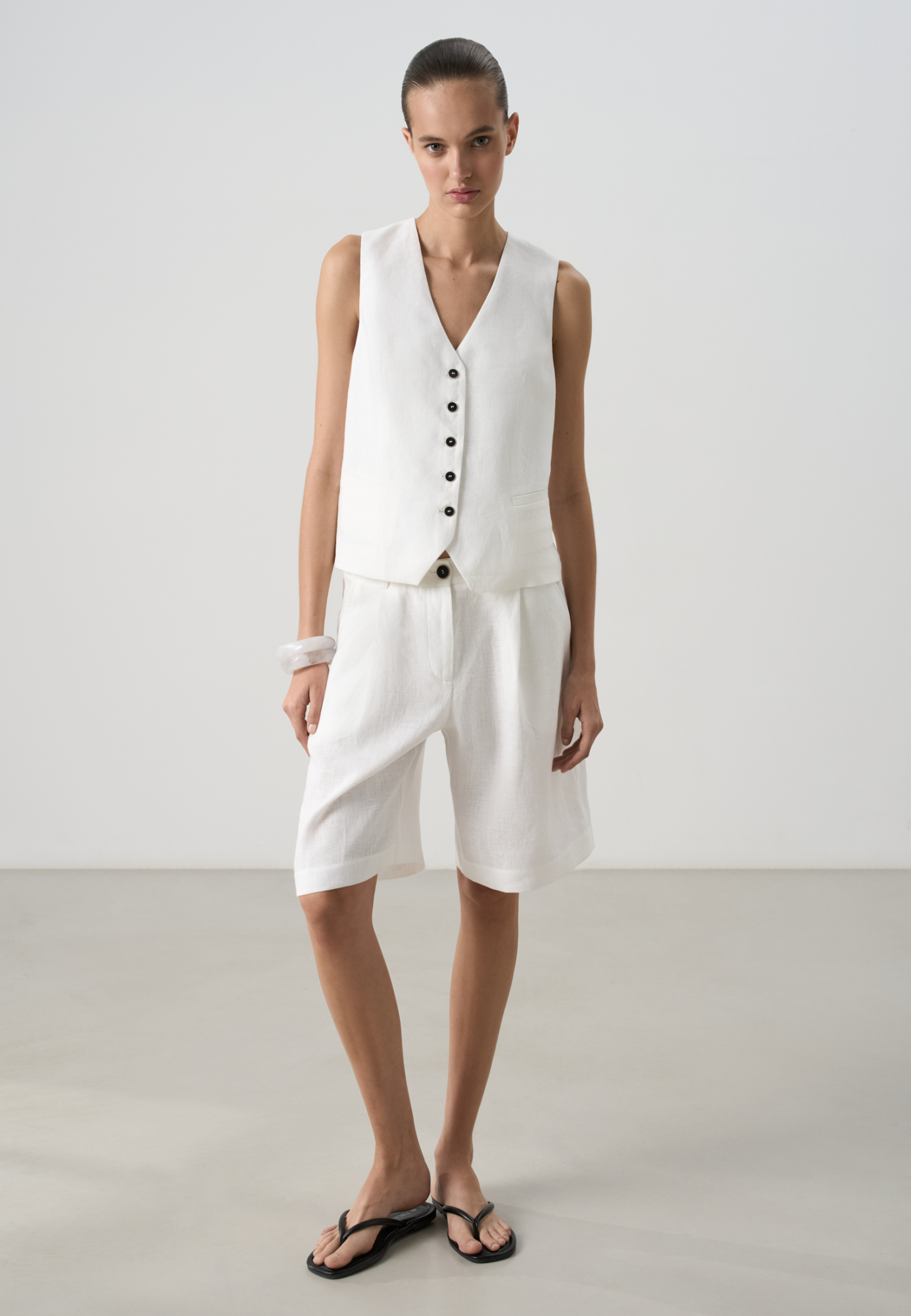 Шорты из 100% льна. Модель с высокой посадкой, широкими штанинами и складками спереди. Два кармана спереди и сзади. Застежка на пуговицу и молнию. Шлевки на поясе для ремня.