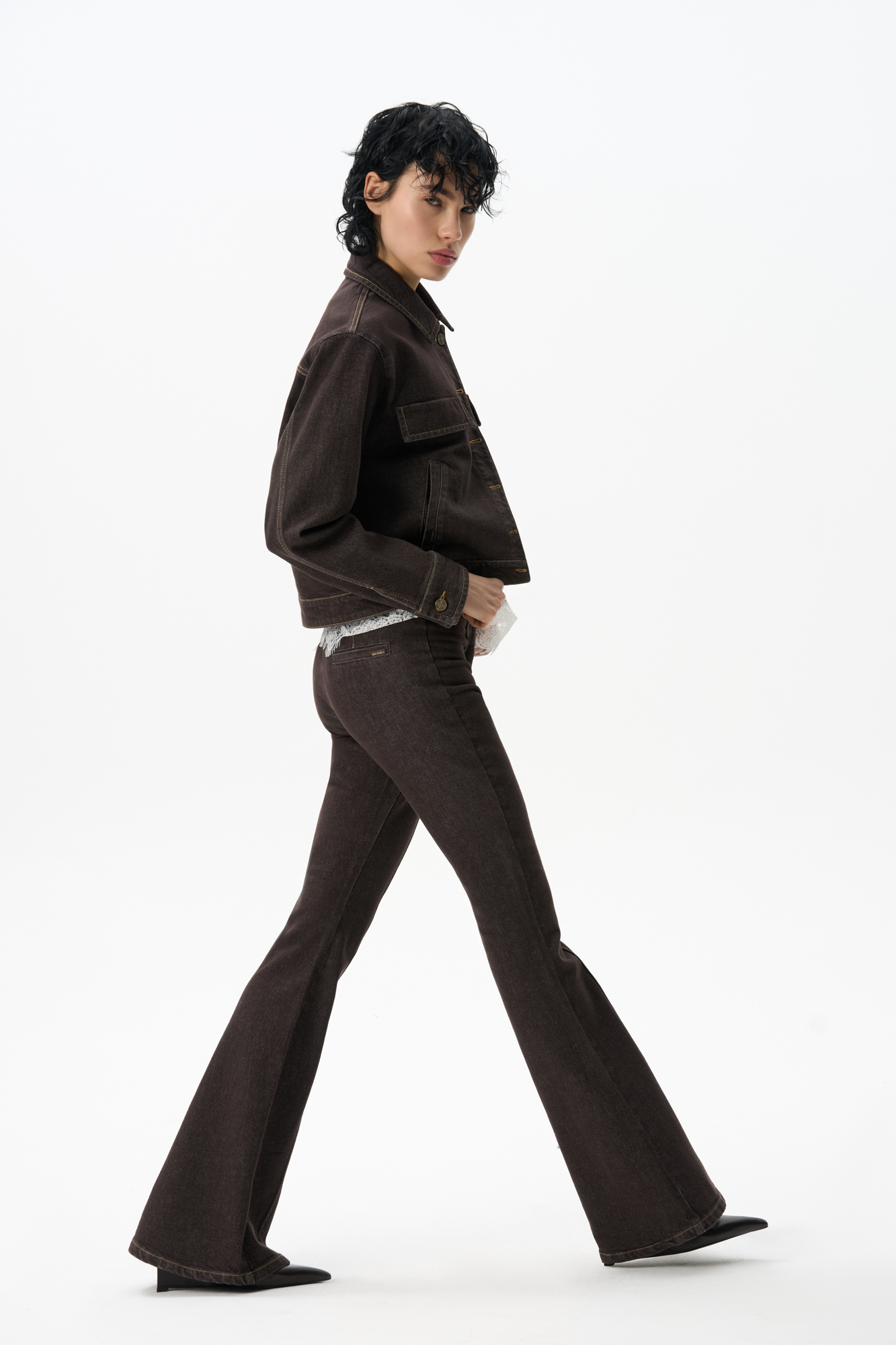 Джинсы клеш из 100% хлопка. Модель облегающего до колен кроя с низкой посадкой и рельефными вертикальными швами. Изделие выполнено без пояса. Застежка на брючный крючок, скрытую пуговицу и молнию.