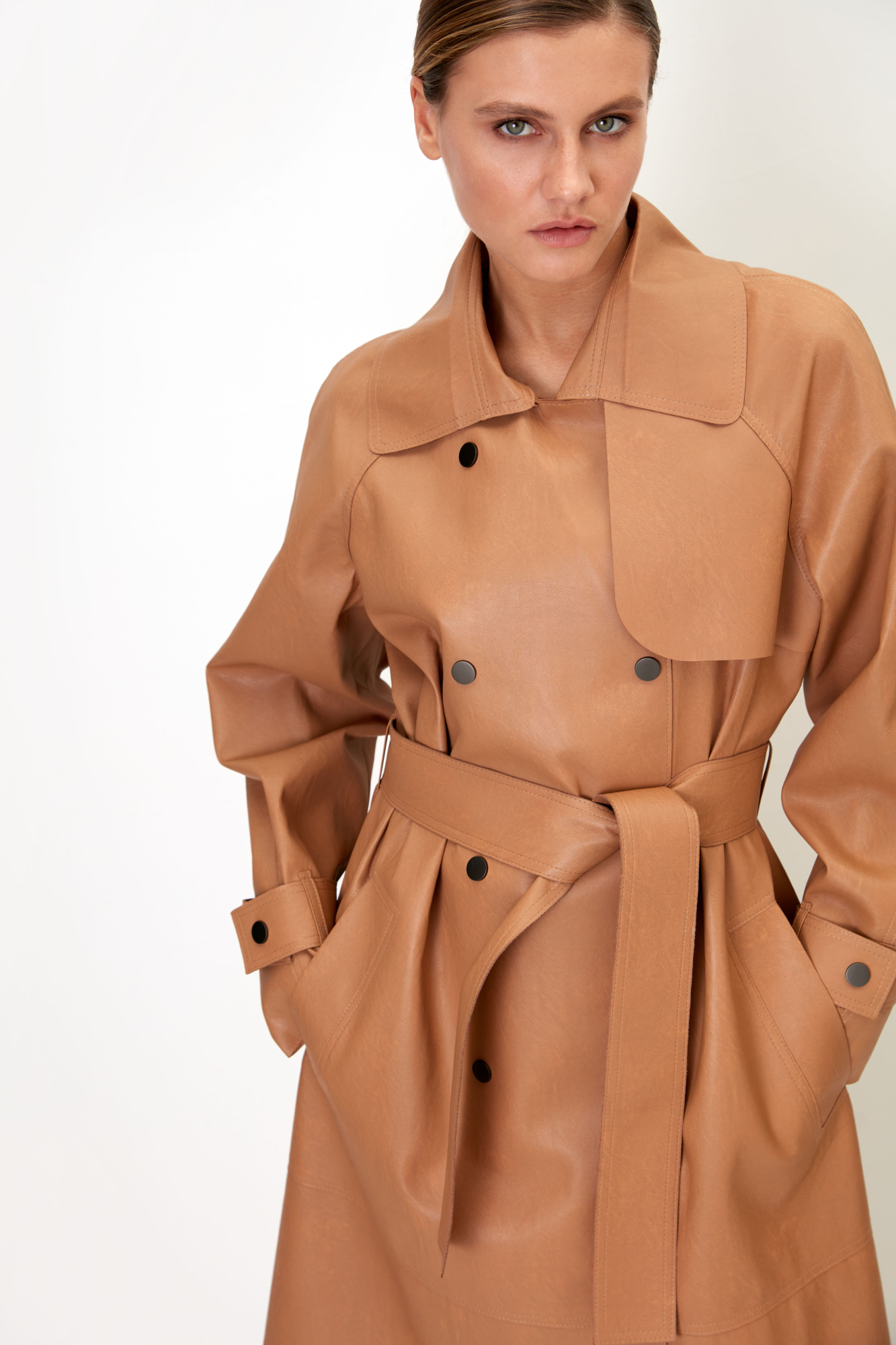 Oversize тренч из двустронней экокожи без подкладки. Модель свободного силуэта с боковыми карманами, симметричной отлетной кокеткой и длинными рукавами с патами на манжетах. В комплекте съемный пояс из основного материала. Застежка на кнопки.