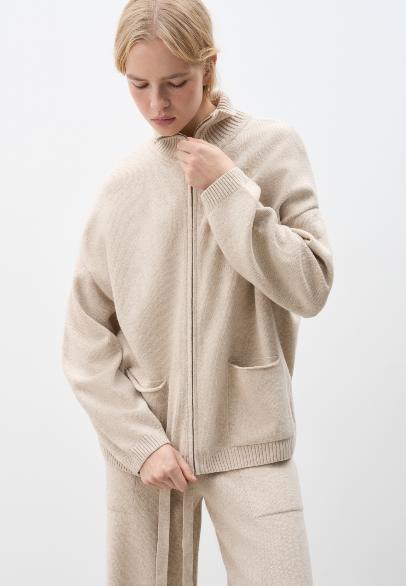 Трикотажный бомбер в спортивном стиле из кашемира и шерсти. Модель свободного силуэта со спущенной линией плеча, накладными карманами и воротником-стойкой. Изделие декорировано вышитым логотипом бренда на груди. Застежка на молнию.