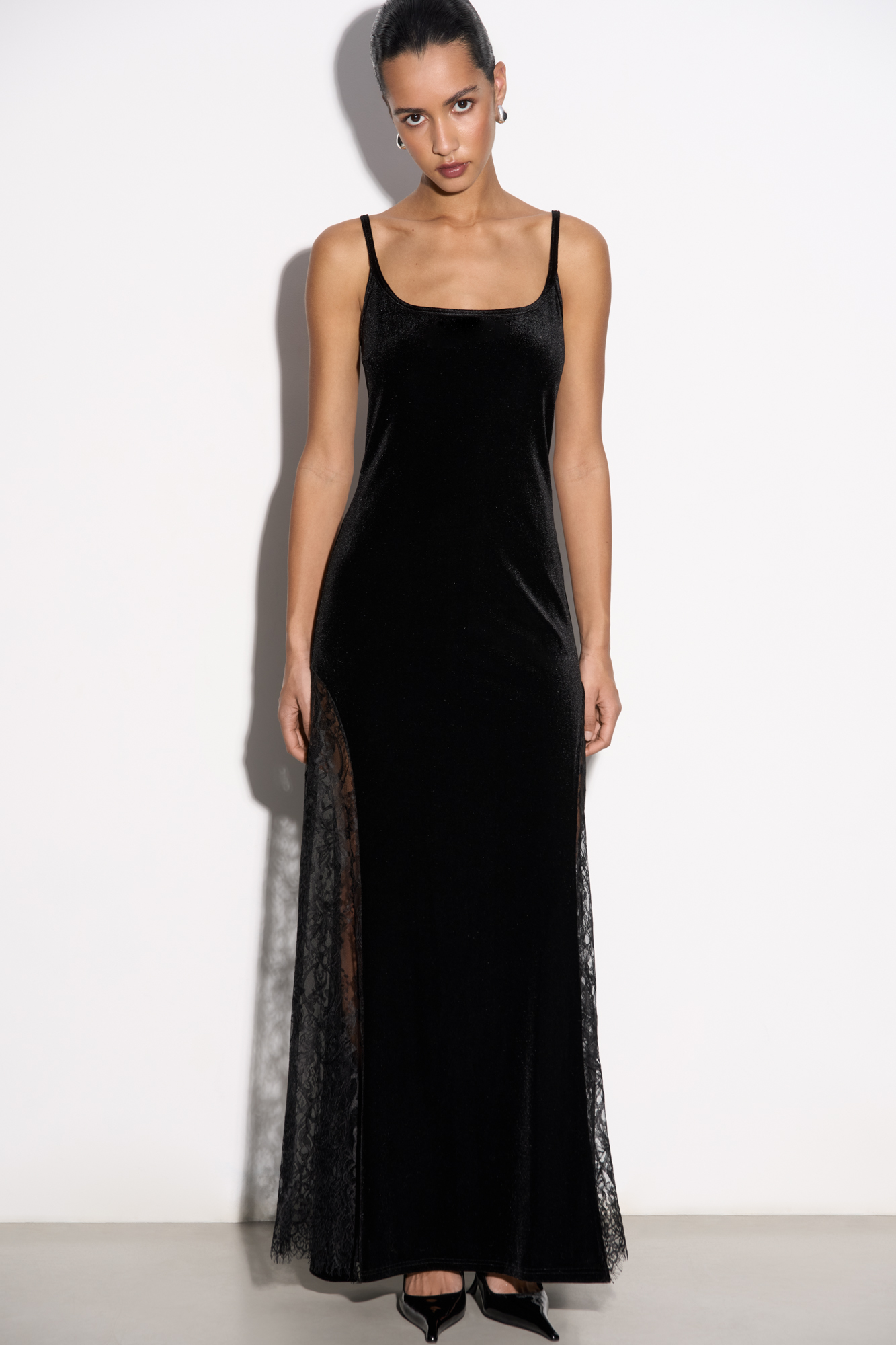 Бархатное платье длины макси с кружевными вставками и вырезом на спине. Модель приталенного силуэта на тонких бретельках. Без застежки.