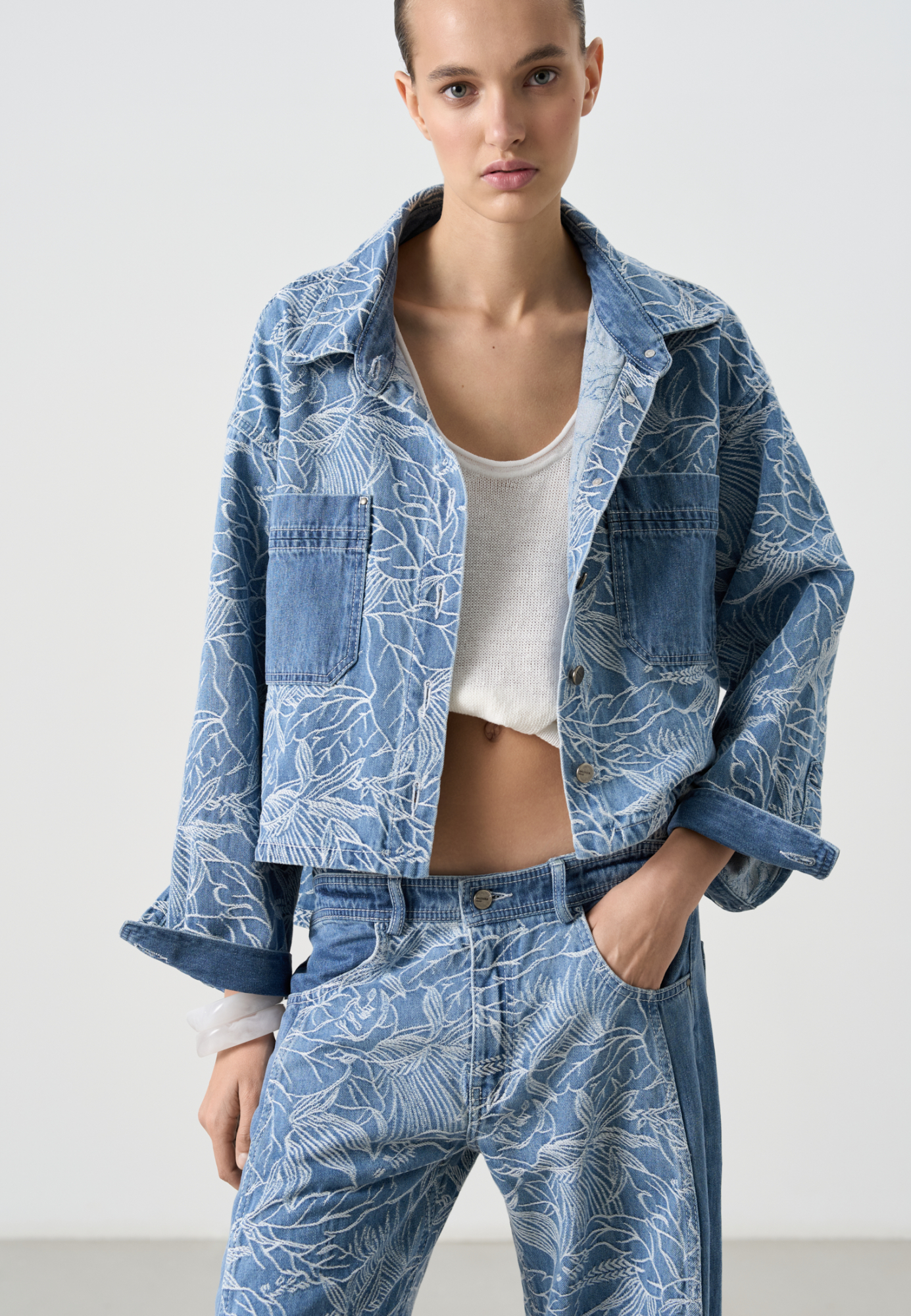 Принтованная джинсовая рубашка из 100% хлопка. Модель укороченного силуэта, с длинными рукавами с манжетами, классическим отложным оротником и двумя нагрудными карманами. Застежка на пуговицы.