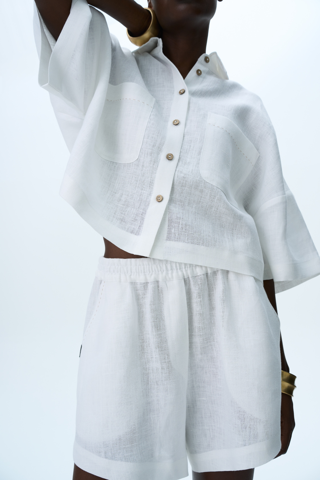 Комплект из 100% льна. Укороченная рубашка с отложным воротником, накладными карманами и спущенной линией плеч. Короткие шорты прямого кроя с боковыми карманами и эластичным поясом на резинке.