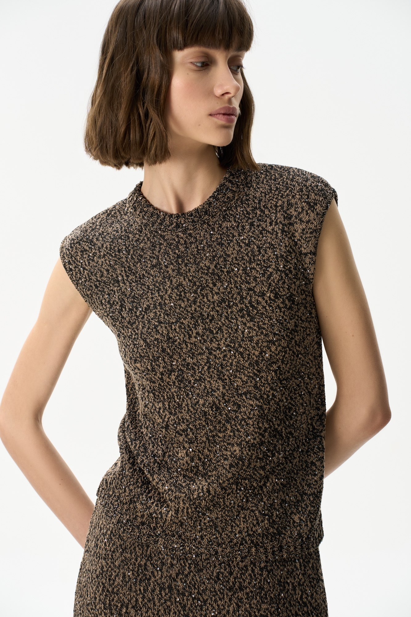 Трикотажный топ из хлопка с пайетками. Модель прямого кроя без рукавов, с круглым вырезом горловины. Края изделия выполнены в рубчик.