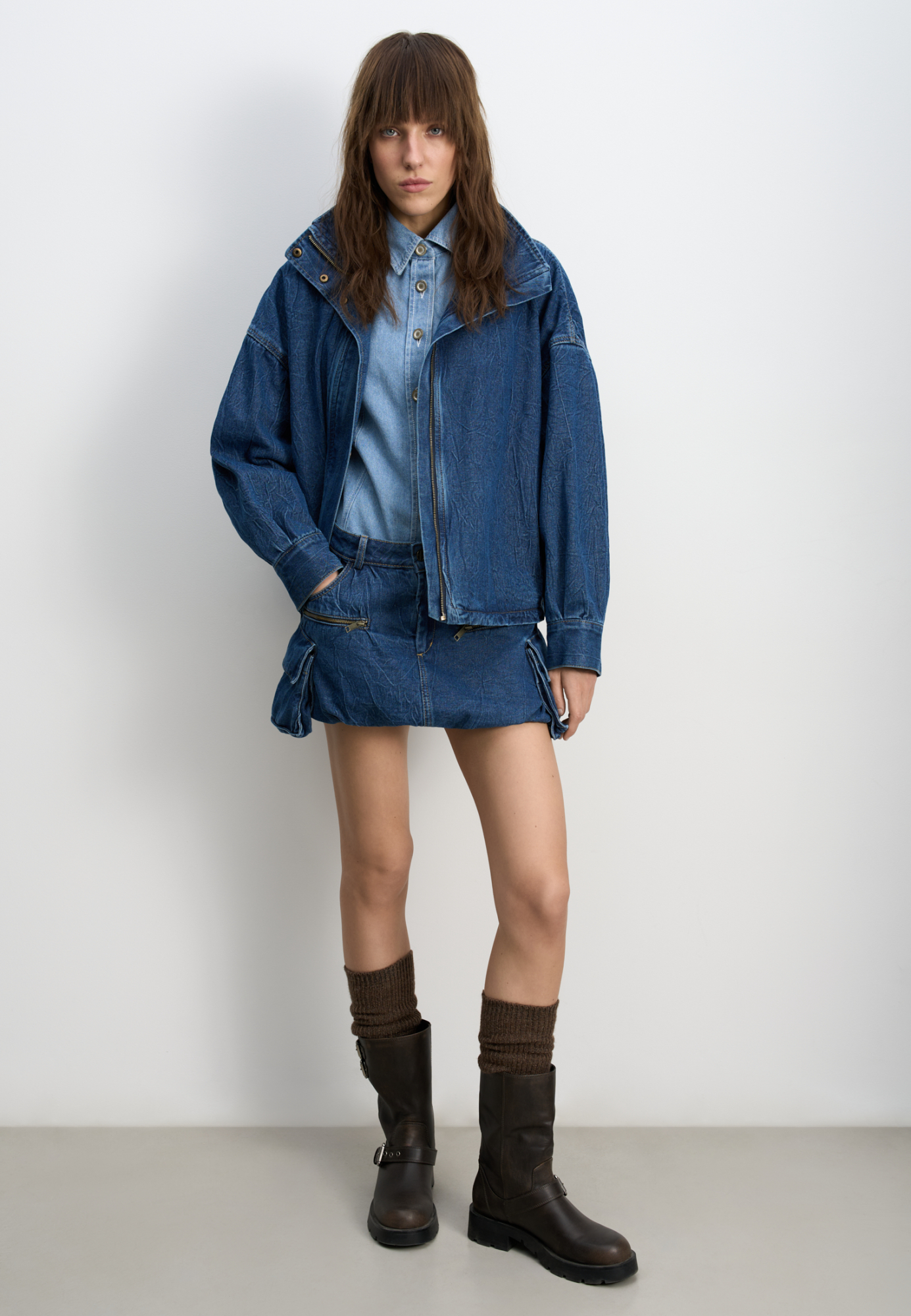 Джинсовая мини-юбка баллон из 100% хлопка. Модель с большими накладными карманами с клапанами по бокам, врезными карманами, шлевками на поясе для ремня и застежкой на молнию и пуговицу. 