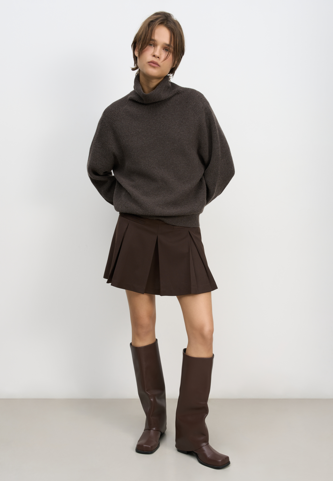 Юбка длины мини из шерсти. Модель прямого кроя, с крупными складками, поясом со шлевками для ремня, врезными карманами спереди и застежкой на молнию. Изделие без подкладки.