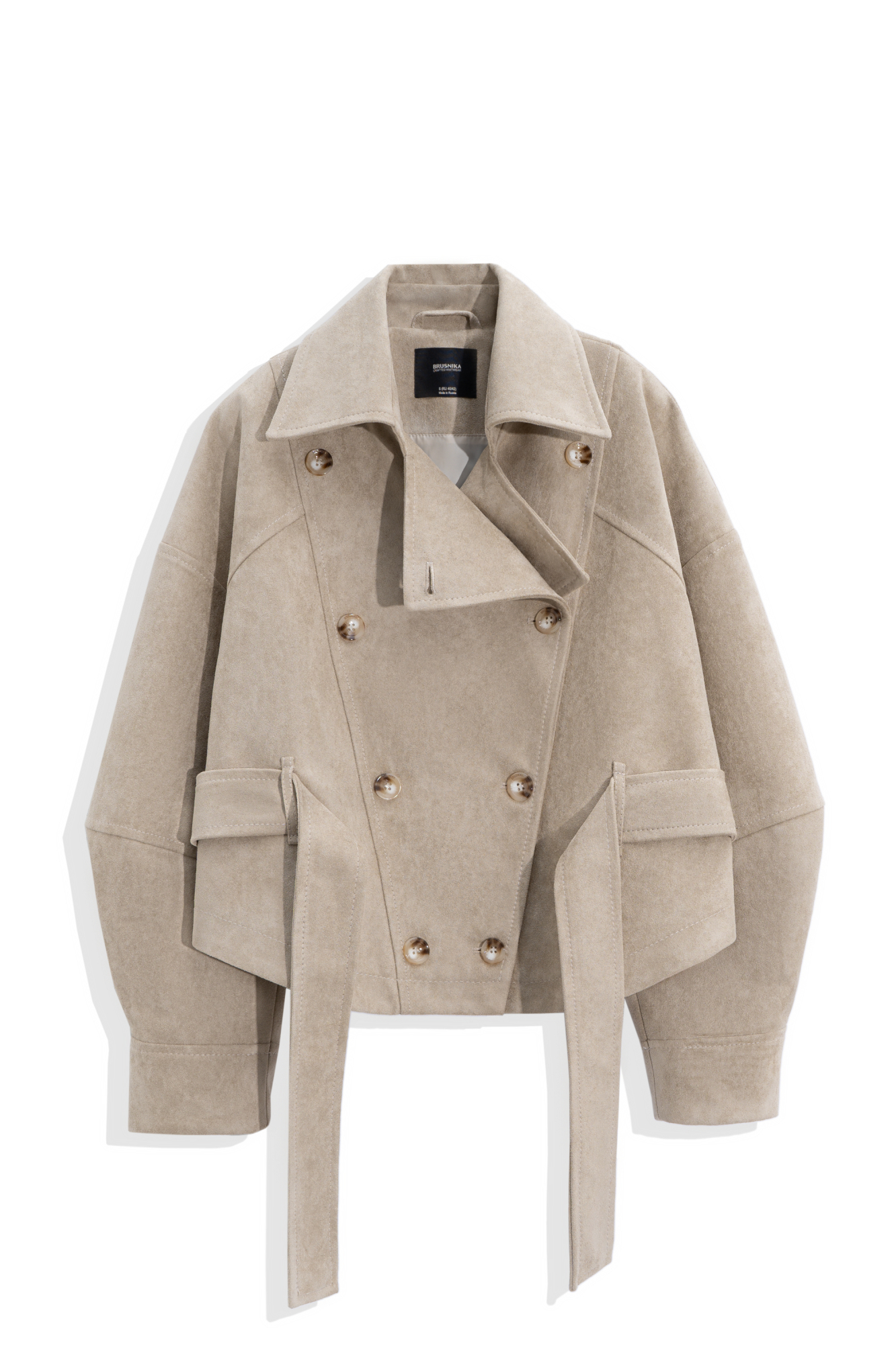 Двубортный короткий тренч сложной геометрии, выполненный из ткани с имитацией внешнего вида и свойств натуральной замши. Модель с отложным воротником, свободными рукавами со спущенной линией плеч, шлевками на поясе и ремнем.