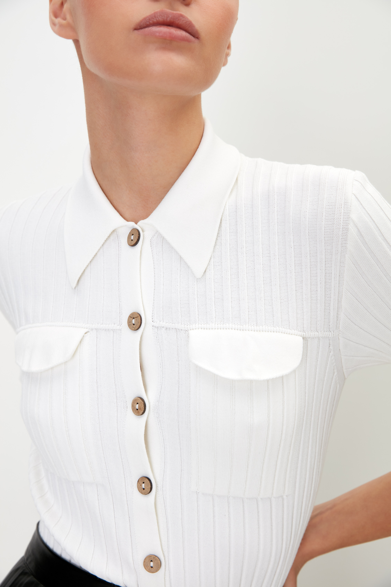 Трикотажная футболка из вискозы в широкий рубчик. Модель приталенного силуэта с отложным воротником, небольшими разрезами на манжетах и имитацией карманов на груди с клапанами. Застежка на пуговицы.