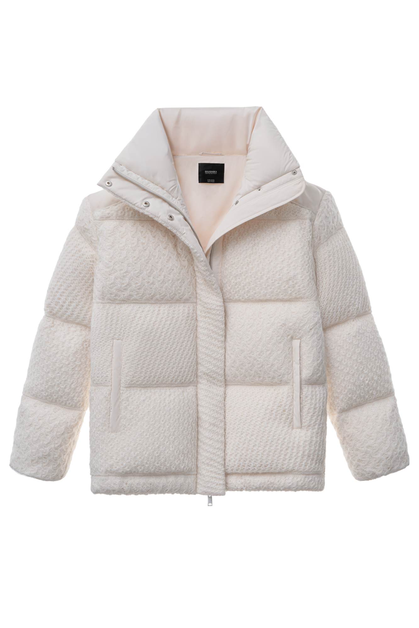 Объемный стеганый пуховик, декорированный комбинированной ажурной вязкой. Модель с воротником-стойкой, боковыми карманами и застежкой на молнию под планкой с кнопками.