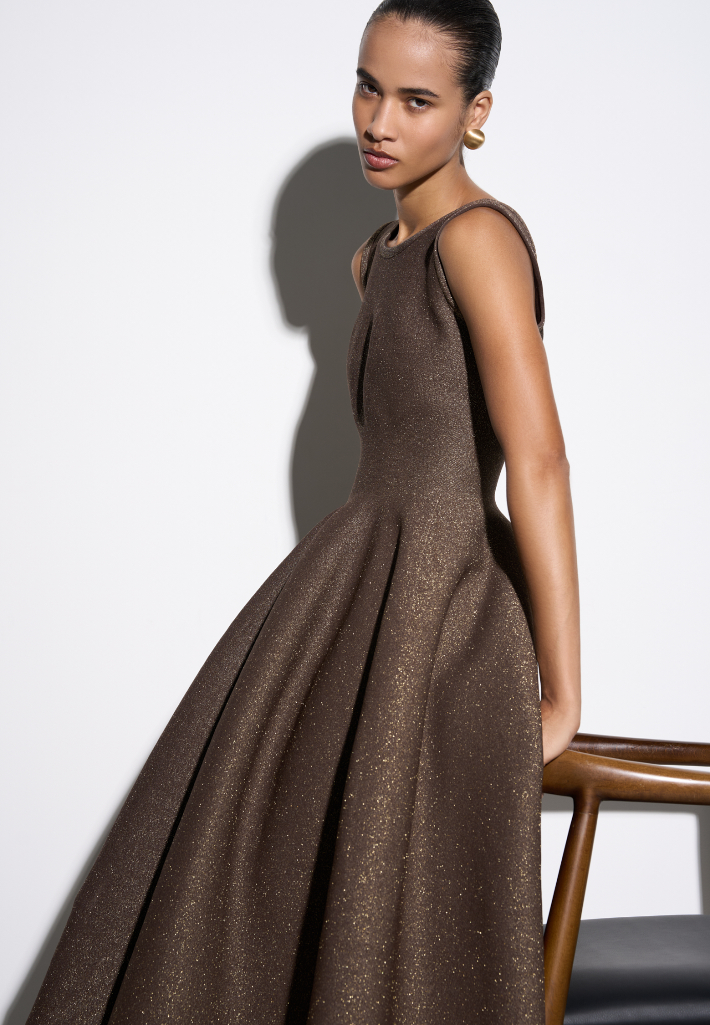 Трикотажное платье длины миди с люрексом. Модель по фигуре с юбкой, расклешенной от талии, без рукавов, на широких бретельках.