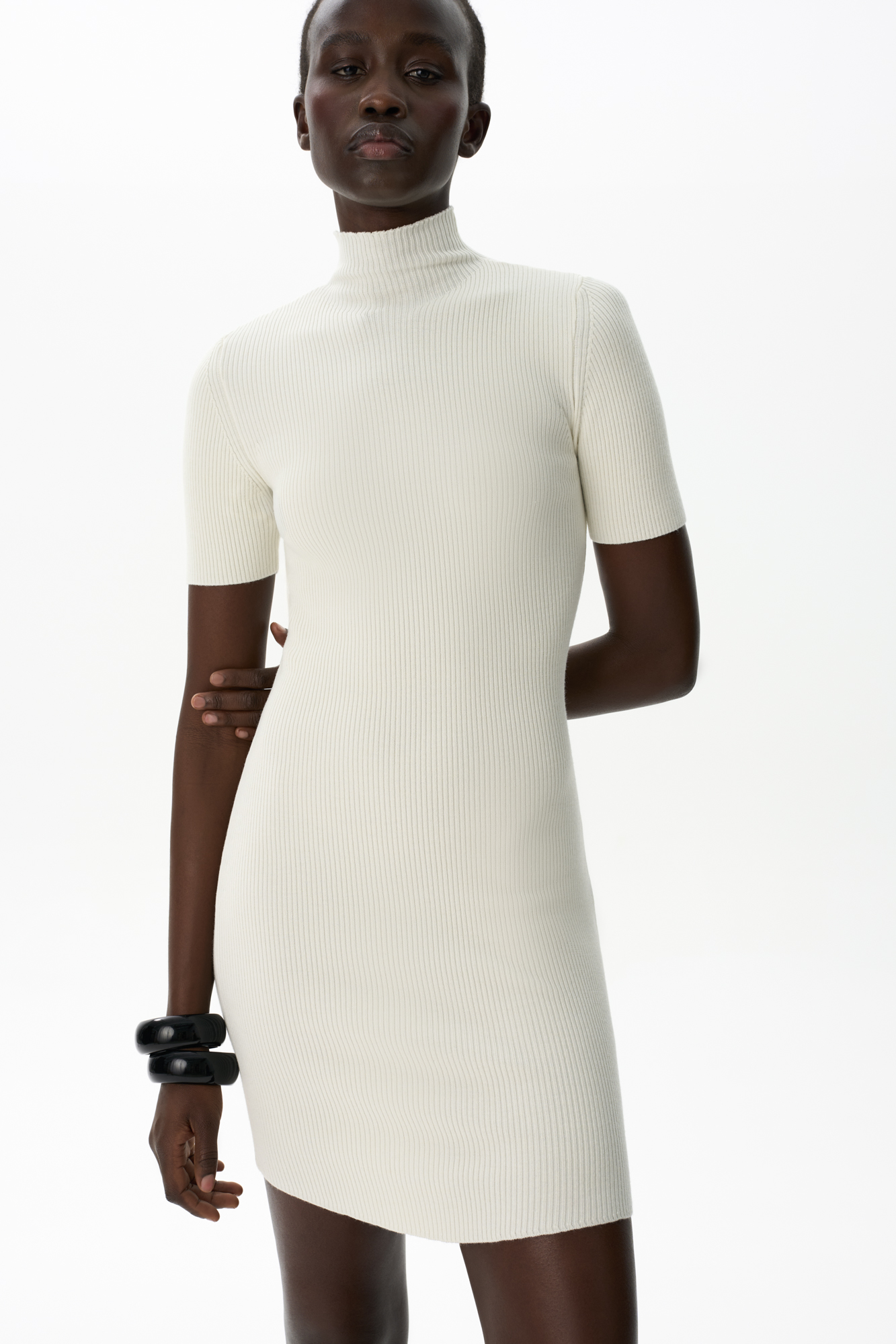 Трикотажное платье длины мини из вискозы с добавлением шерсти. Модель приталенного силуэта с коротким рукавом, невысоким воротником и арочным низом. Изделие выполнено в рубчик.