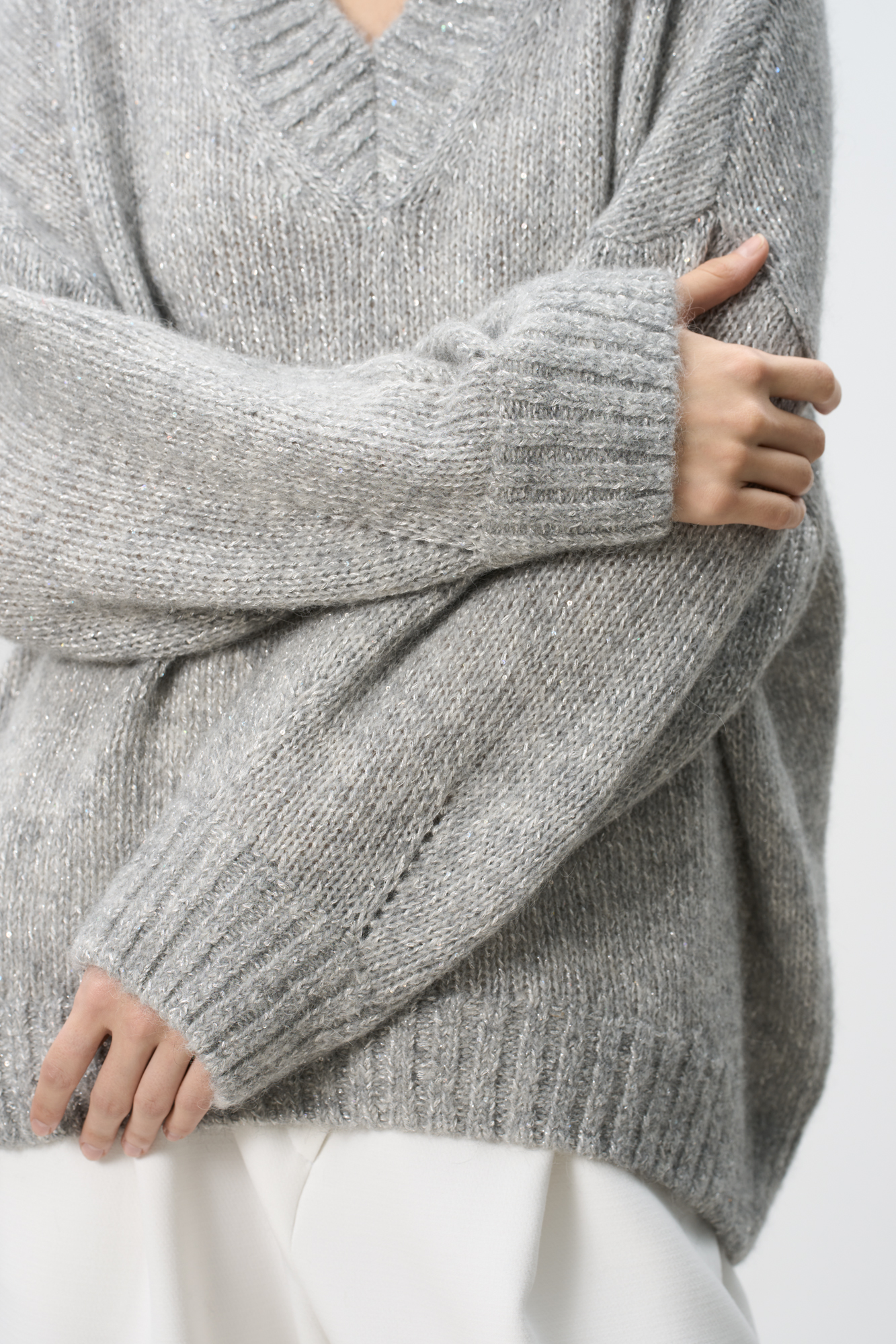 Трикотажный джемпер из шерсти альпака с добавлением люрекса. Модель с V-вырезом, спущенной линией плеча и декоративными сбавками на манжетах. Изделие декорировано пайетками.