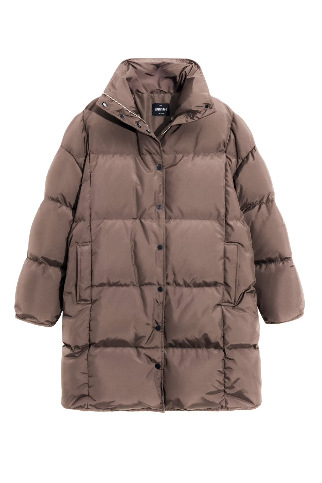 Длинный стеганый пуховик с капюшоном на кулиске. Модель свободного силуэта с воротником-стойкой, трикотажными манжетами и боковыми карманами. Застежка на молнию под планкой с брендированными пуговицами.