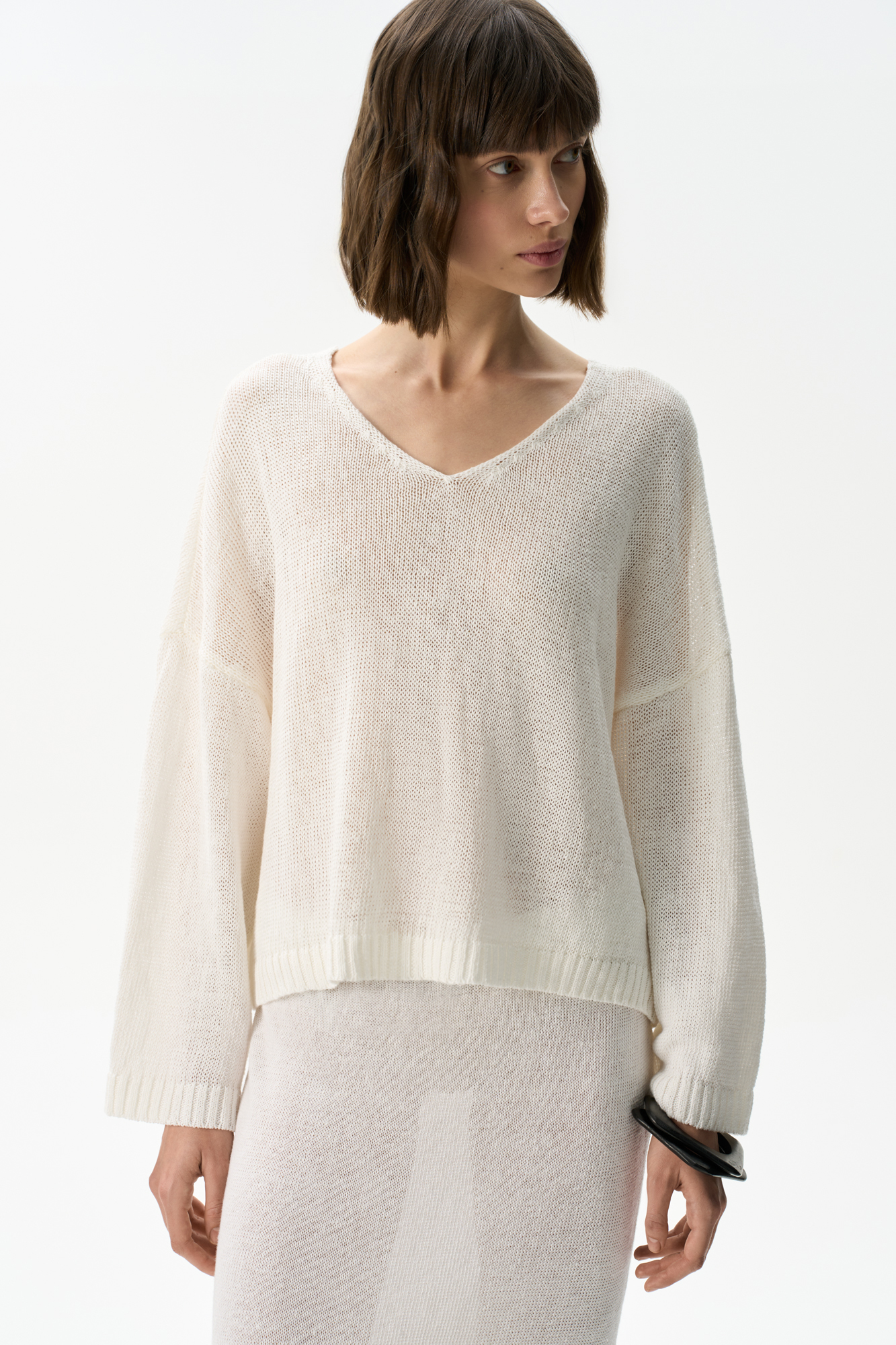 Трикотажный джемпер из 100% льна с V-образным вырезом. Модель прямого силуэта с длинным рукавом и удлиненной спинкой. Края изделия выполнены в рубчик.