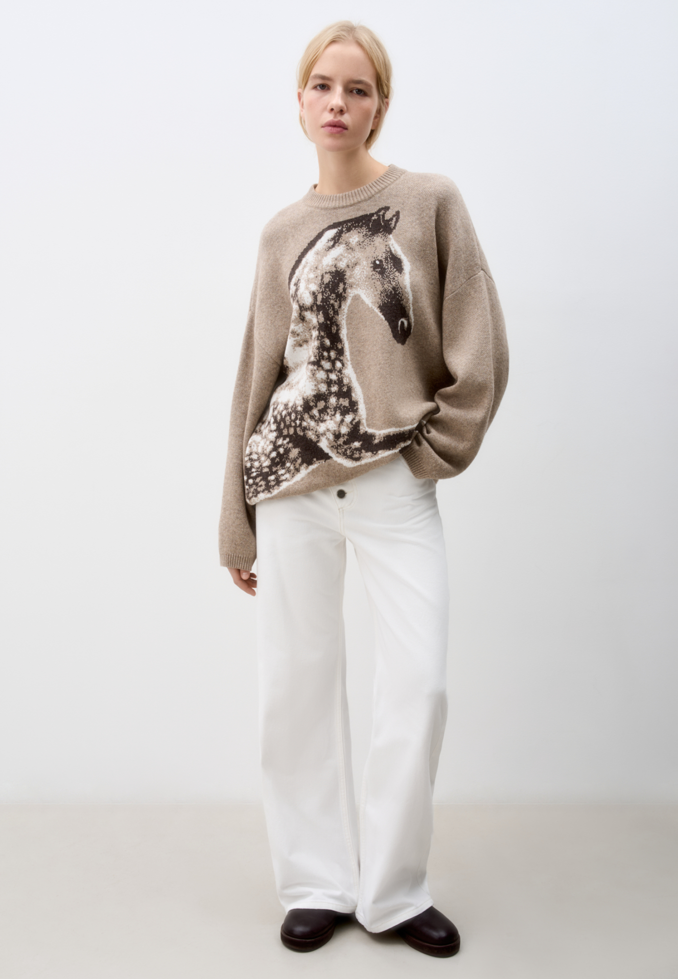 Трикотажный джемпер из шерсти и кашемира. Модель свободного силуэта со спущенной линией плеч, круглым вырезом горловины и жаккардовым анималистичным принтом лошади. Края изделия выполнены в рубчик.