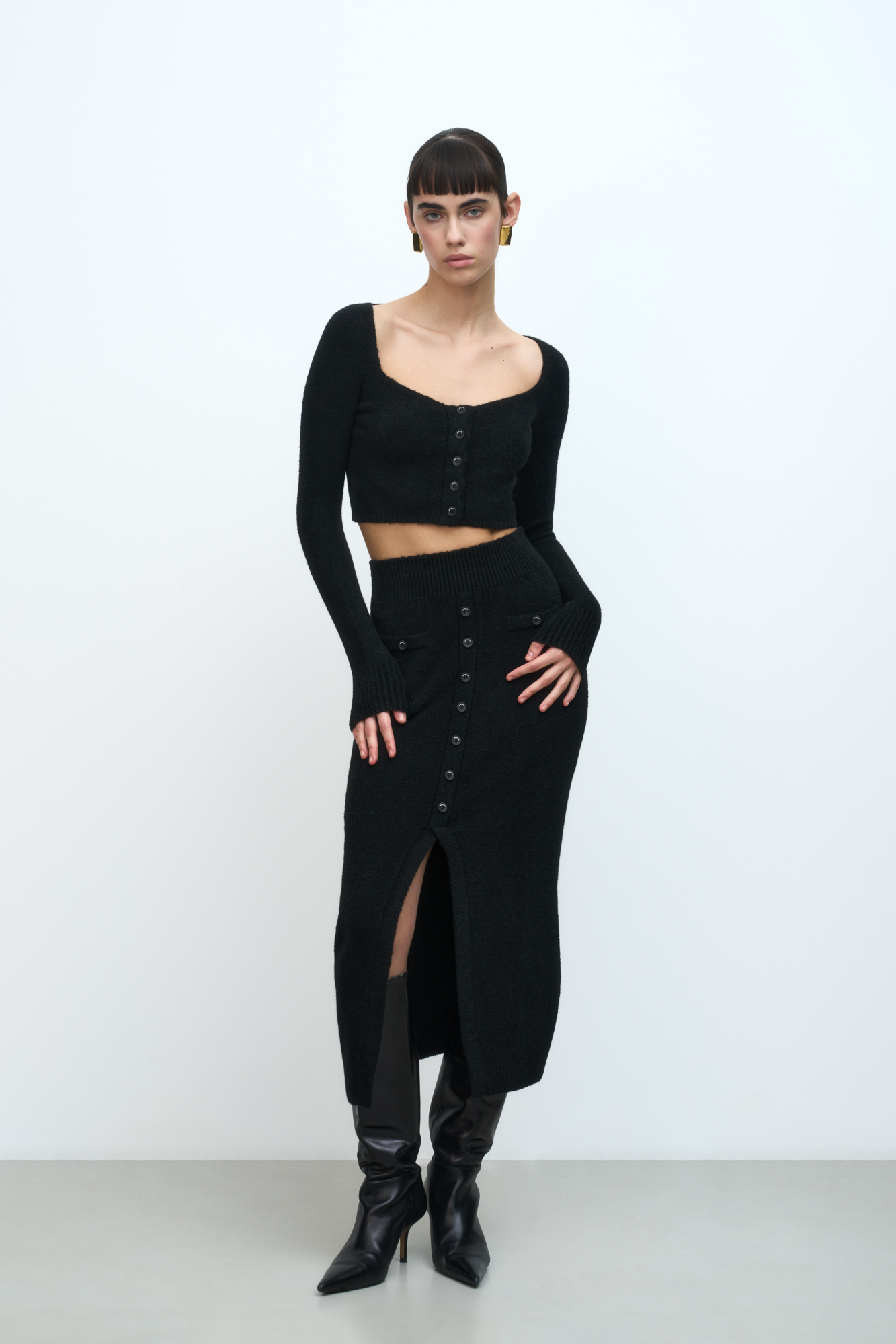 Трикотажная юбка из буклированной пряжи. Модель прямого силуэта с разрезом, декорированным пуговицами. Края изделия выполнены в рубчик. Широкий эластичный пояс.