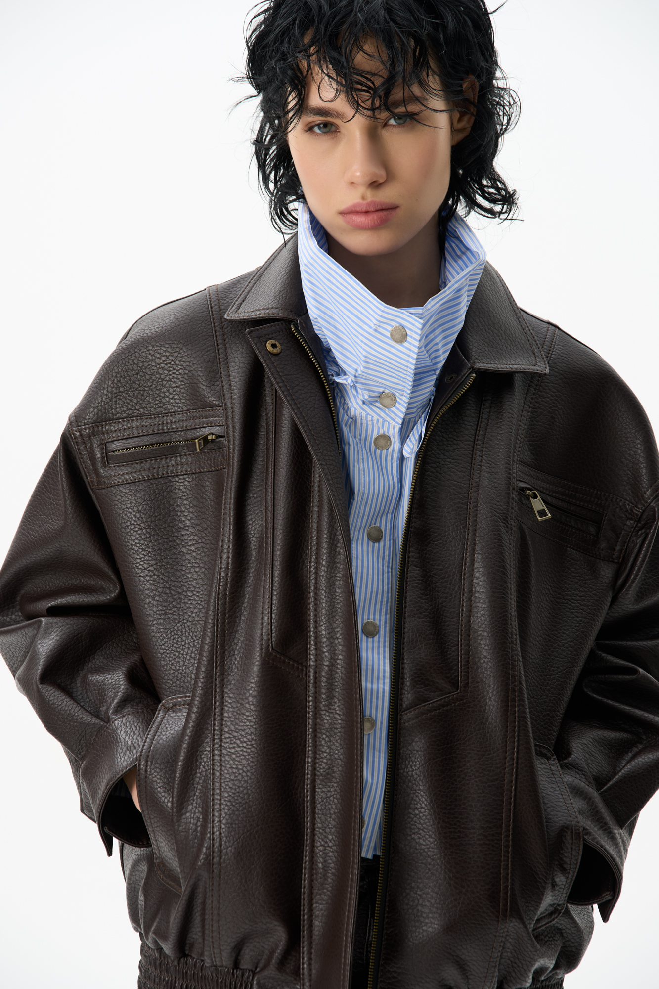 Бомбер из текстурной экокожи. Модель свободного силуэта с длинными рукавами, отложным воротником, двумя нагрудными карманами на молниях и глубокими боковыми карманами. Застежка на молнию и металлические кнопки на планке. Изделие на подкладке.