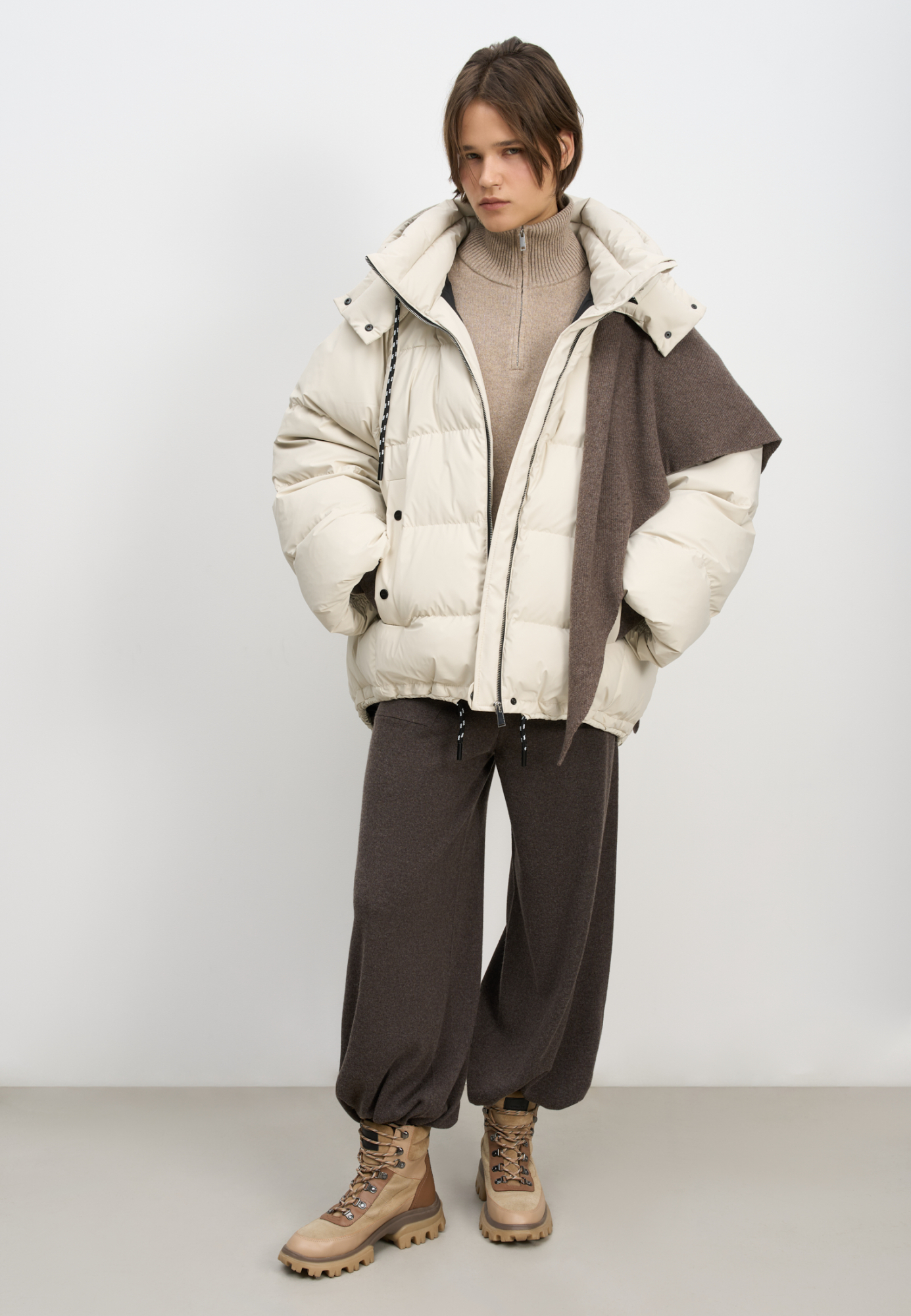 Объемный стеганый пуховик. Модель свободного силуэта с боковыми карманами на кнопках, воротником-стойкой и капюшоном. Низ изделия выполнен на регулируемой кулиске. Застежка на молнию и кнопку.