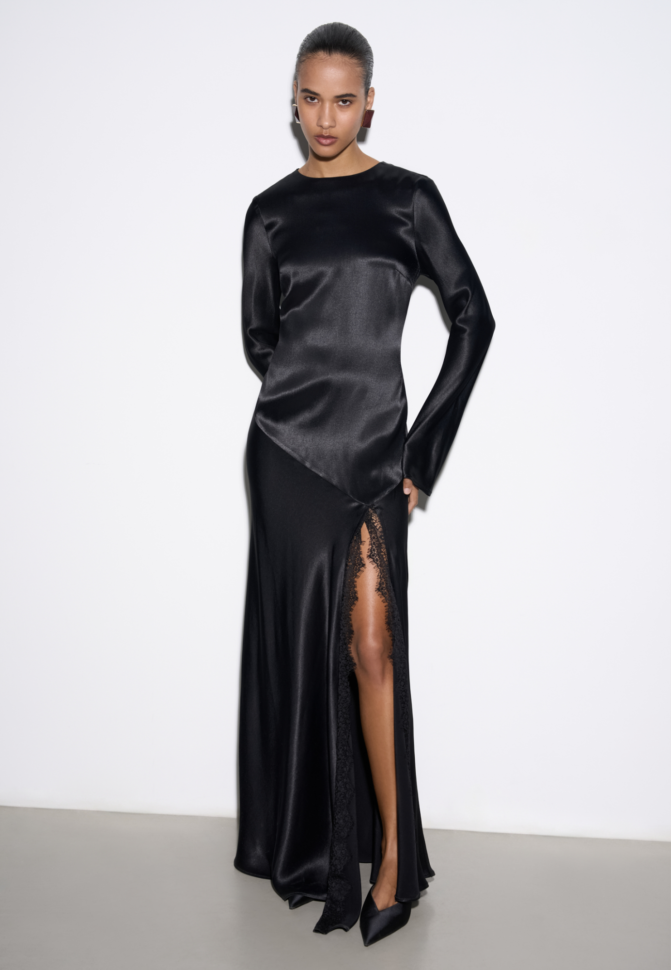 Платье длины макси из атласной вискозы. Модель приталенного силуэта с длинными рукавами и круглым вырезом. Высокий разрез на юбке декорирован кружевом.