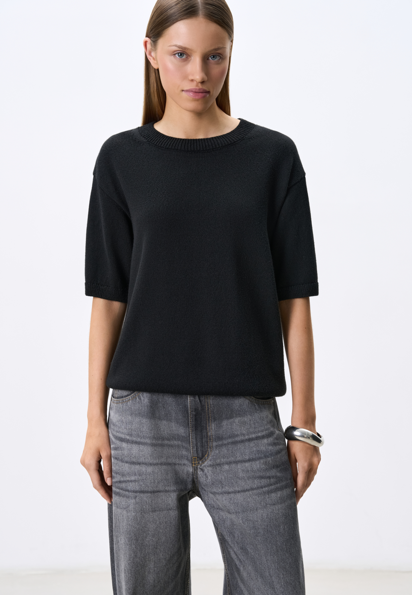 Трикотажная футболка из хлопка с добавлением вискозы. Модель свободного силуэта, со спущенной линией плеч и круглым вырезом горловины. Края изделия выполнены в рубчик.