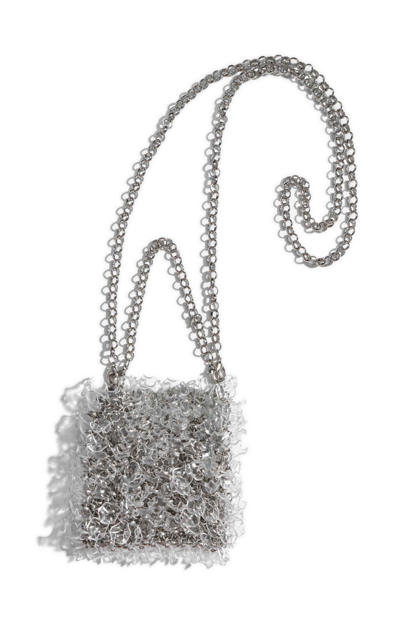 Сумочка, выполненная путем переплетения металлических колец и декорированная прозрачными бусинами неправильной формы. Модель с двумя ремешками-цепочками на карабинах. Высота изделия составляет 12 см, длина ручки - 12 см, длина цепочки - 109 см.