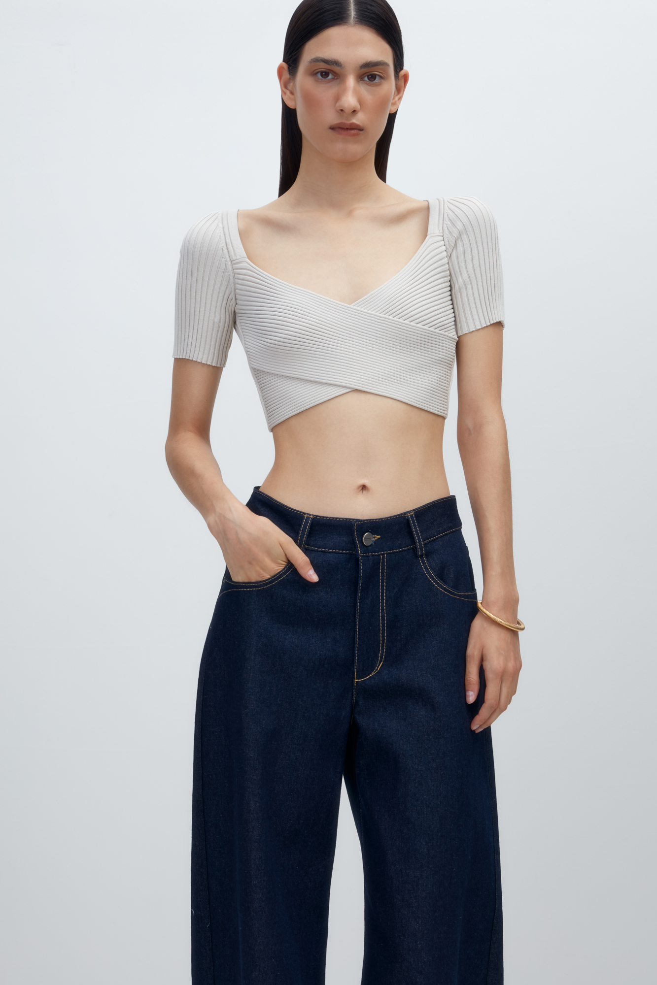 Короткий трикотажный топ из вискозы. Модель приталенного силуэта, с коротким рукавом, глубоким вырезом и скрещенным лифом. Изделие выполнено в рубчик.