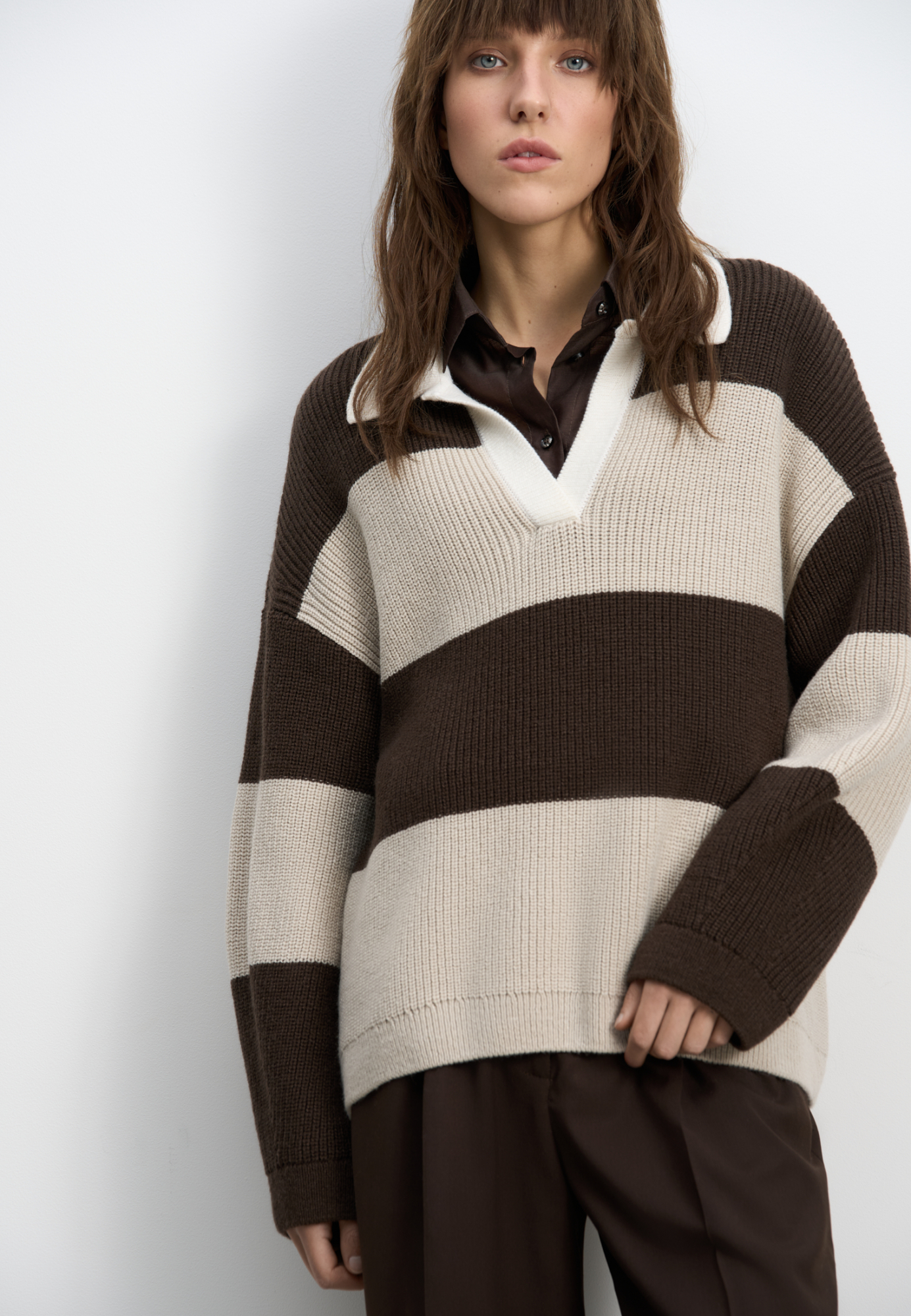 Трикотажный джемпер из шерсти в полоску. Модель свободного силуэта, со спущенной линией плеч, длинными рукавами, отложным воротничком контрастного цвета и V-образным вырезом горловины.