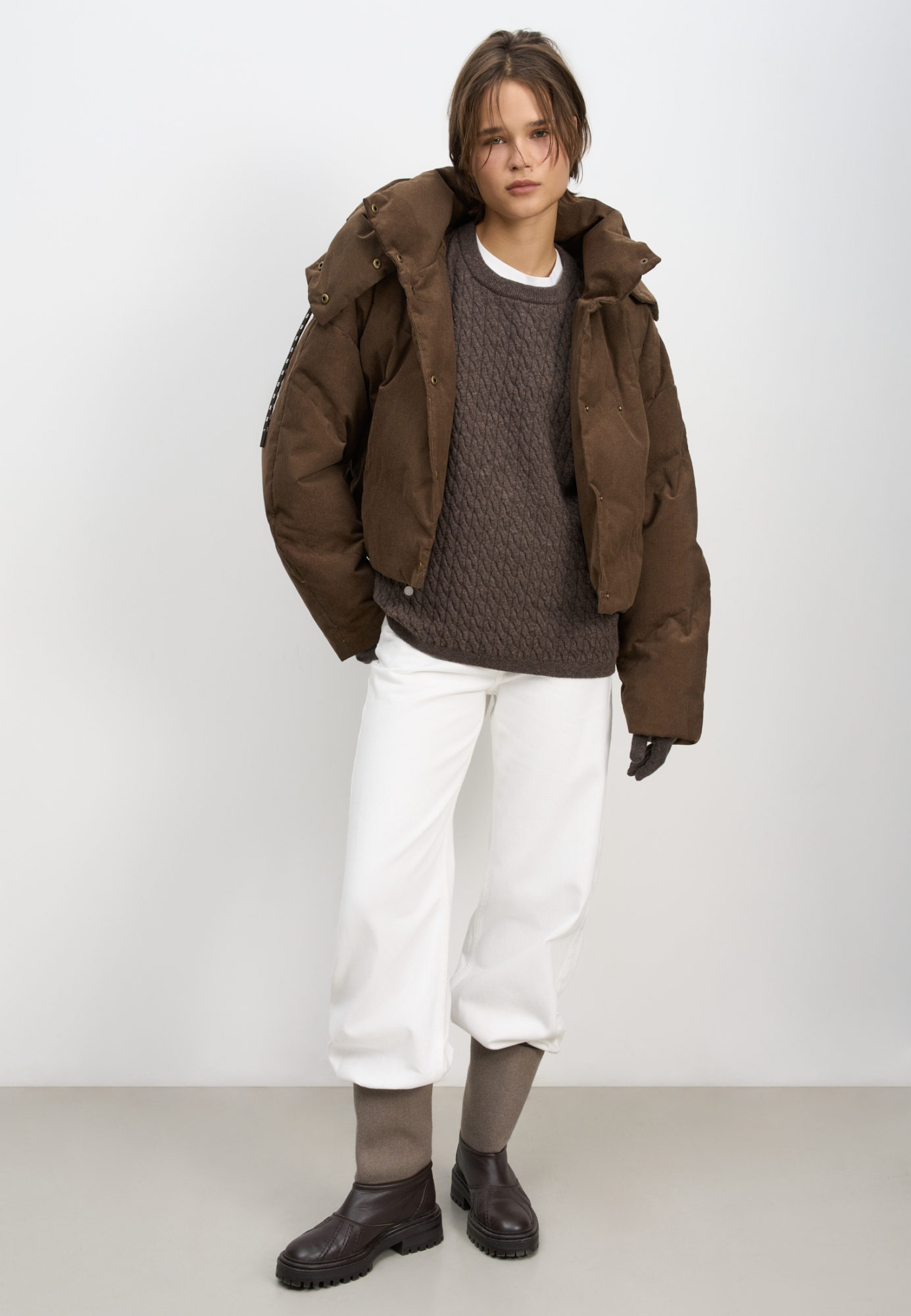 Пуховик с воротником-стойкой, съемным капюшоном и графичной стежкой с двойной отстрочкой. Модель имеет два варианта застежки на металлические кнопки. Низ изделия выполнен на кулиске.