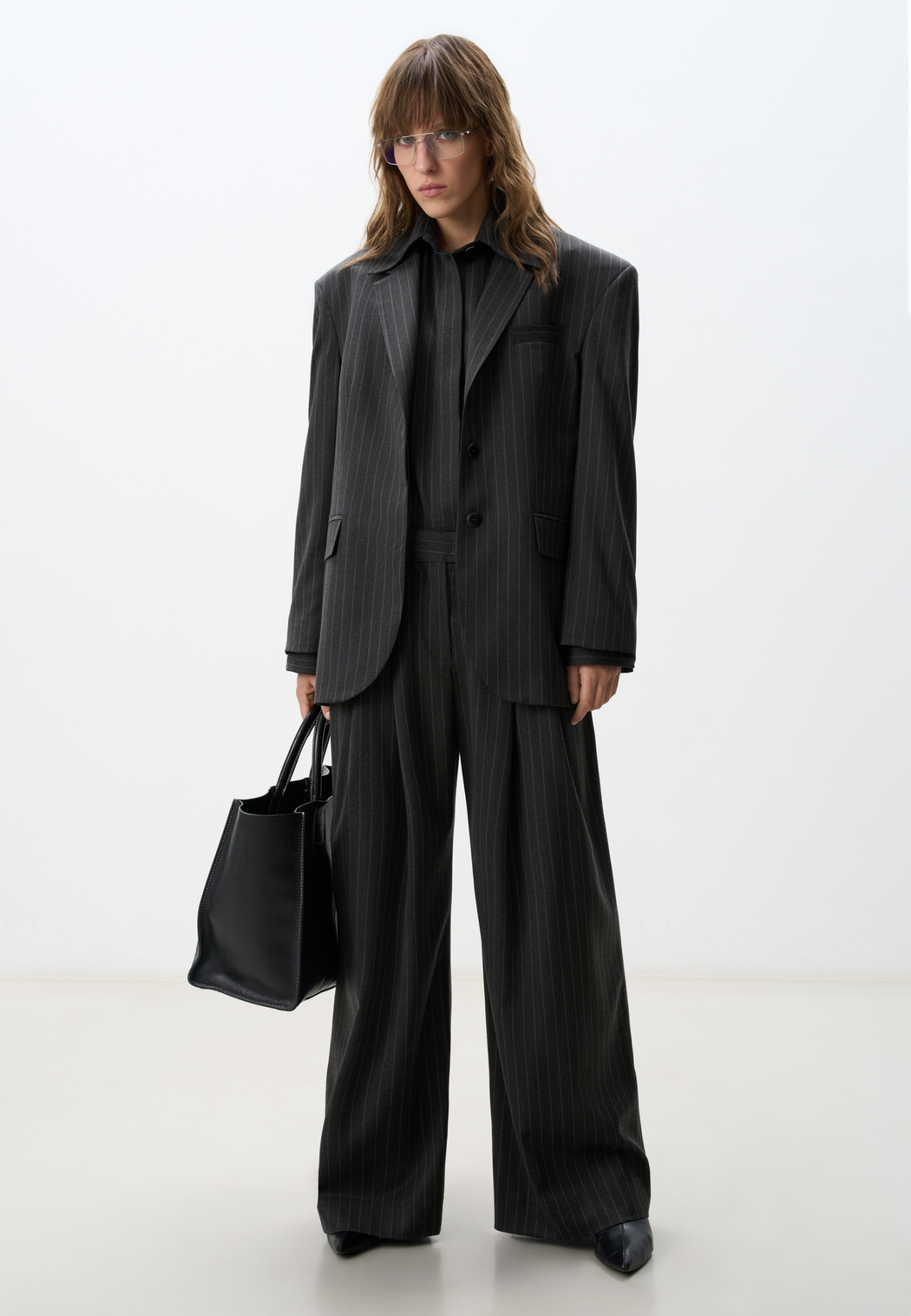 Широкие офисные брюки из полушерсти. Модель свободного кроя с защипами спереди, карманами, шлевками на поясе для ремня и застежкой на молнию и скрытую пуговицу. Дополнить образ можно жакетом и рубашкой.