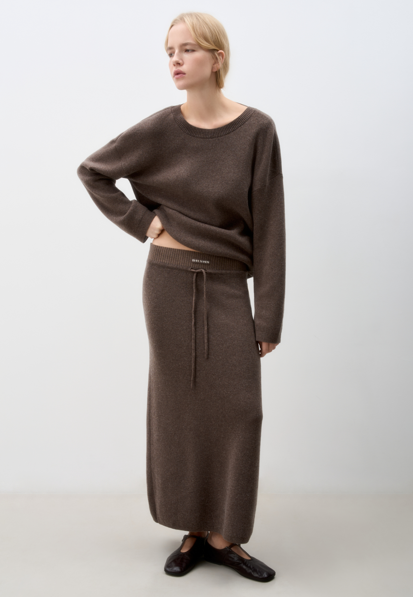 Трикотажная юбка длины макси из кашемира и шерсти. Модель по фигуре, с широким эластичным поясом в рубчик, дополненным кулиской и двумя накладными карманами сзади. Модель декорировано вывязанным логотипом