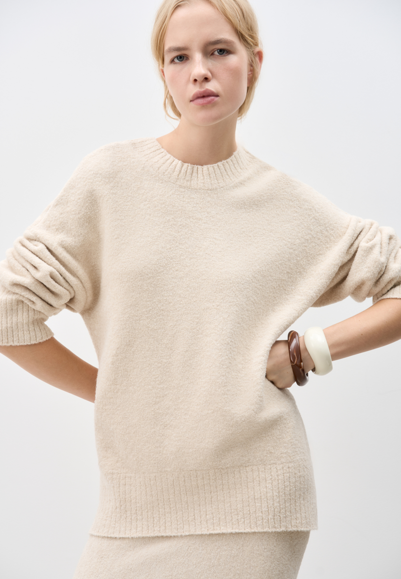 Трикотажный джемпер из буклированной пряжи. Модель свободного силуэта с длинным рукавом и глубоким вырезом на спине. Края изделия выполнены в рубчик. Дополнить образ можно юбкой в таком же стиле.