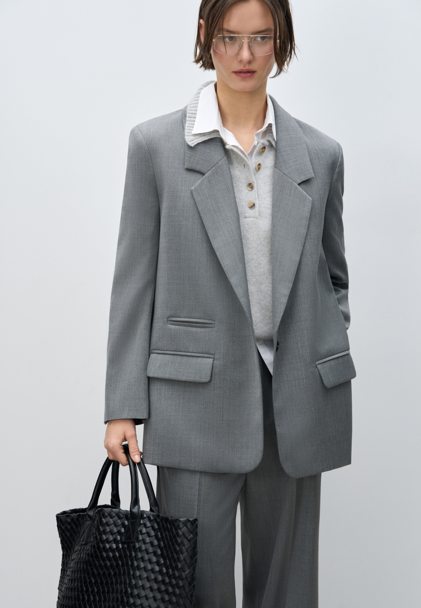Классический жакет с накладными карманами, подплечниками, разрезами по бокам и удлиненной спинкой. Длинные рукава на манжетах без пуговиц. Застежка на пуговицу.