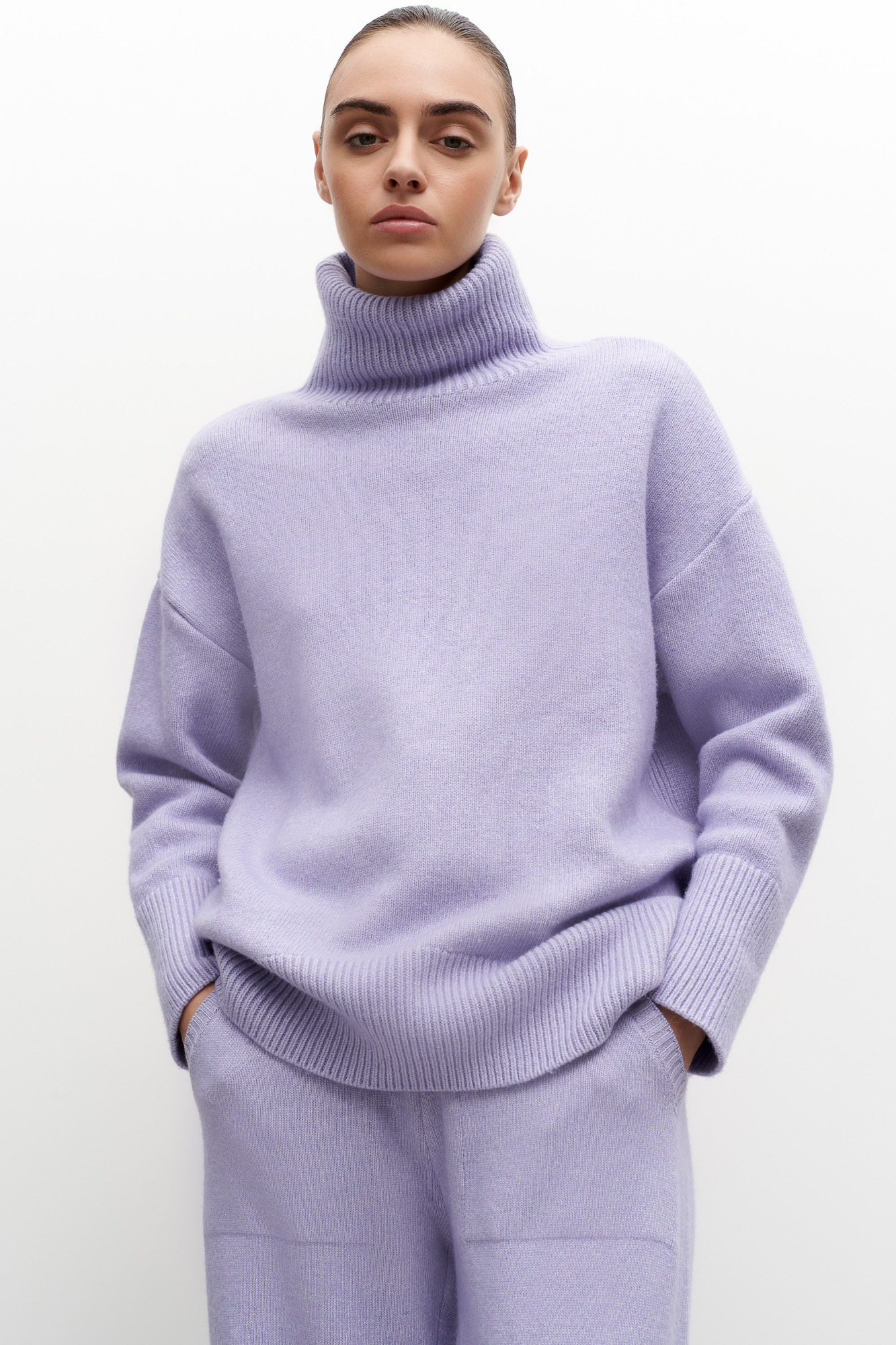 Трикотажный джемпер из мягкой шерсти с добавлением кашемира. Высокий ворот, заниженная линия плеч, удлиненная спинка. Края изделия сделаны в широкий рубчик. Можно дополнить комплектными брюками.