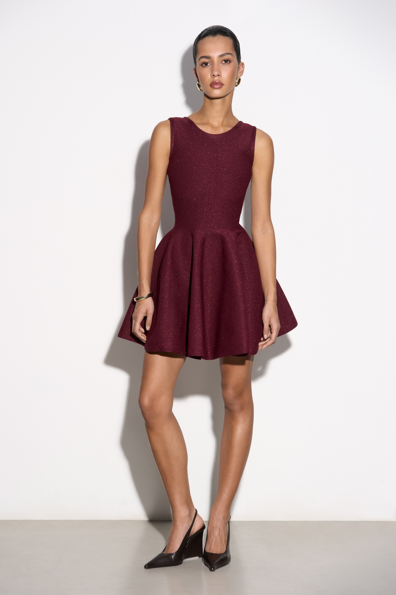 Трикотажное платье длины мини с люрексом. Модель по фигуре с юбкой, расклешенной от талии, без рукавов, на широких бретельках.