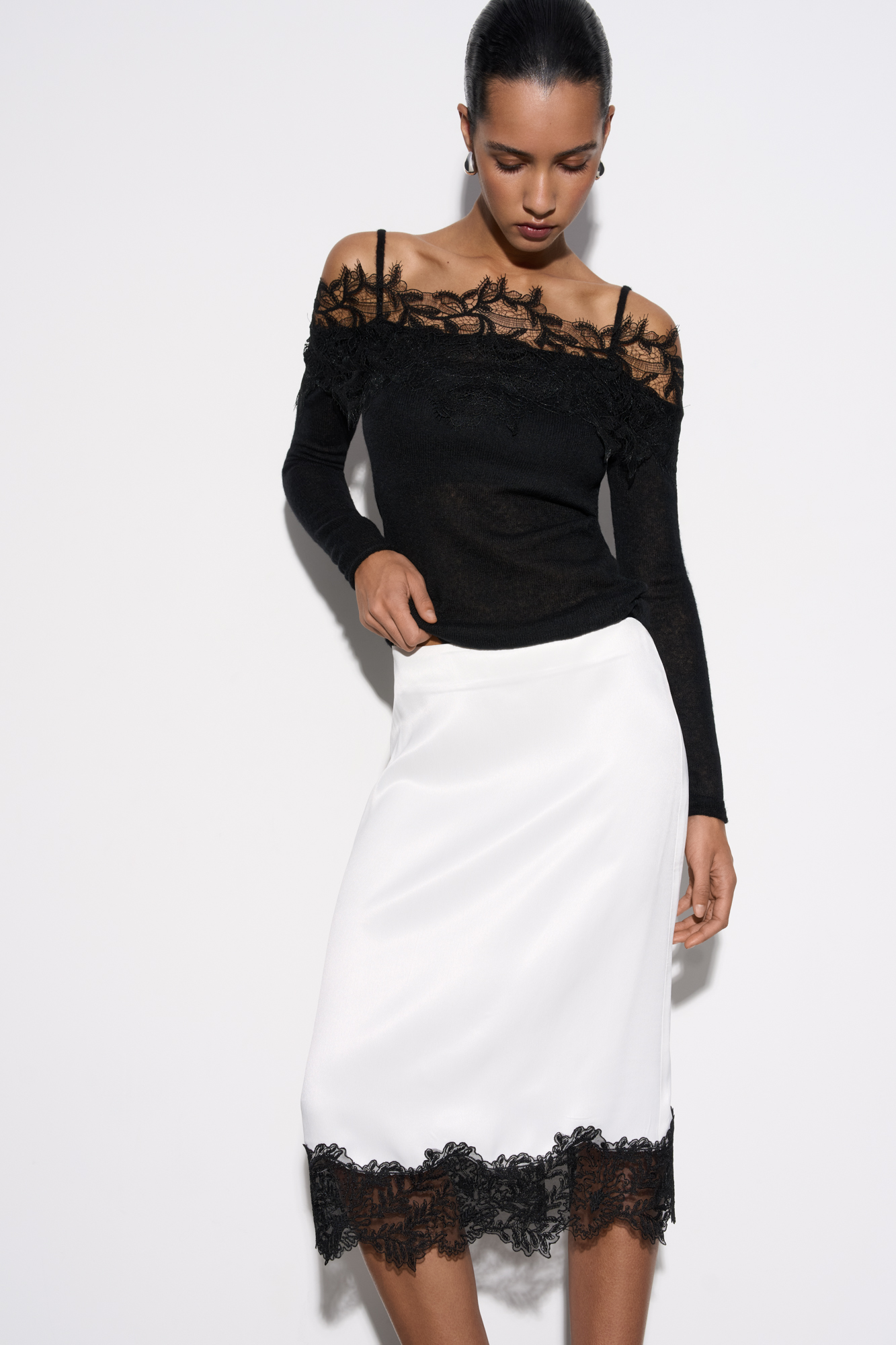 Юбка длины миди из атласной вискозы. Подол изделия декорирован тонким кружевом контрастного цвета. Застежка на потайную молнию.