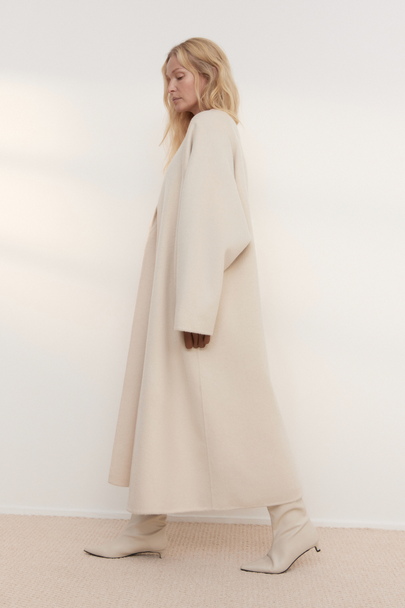 Шерстяное пальто из двусторонней ткани. Модель прямого кроя без воротника. Застежка на скрытые магнитные пуговицы. Изделие без подкладки. Модель декорирована асимметричным лацканом. Пояс из экокожи в комплекте.