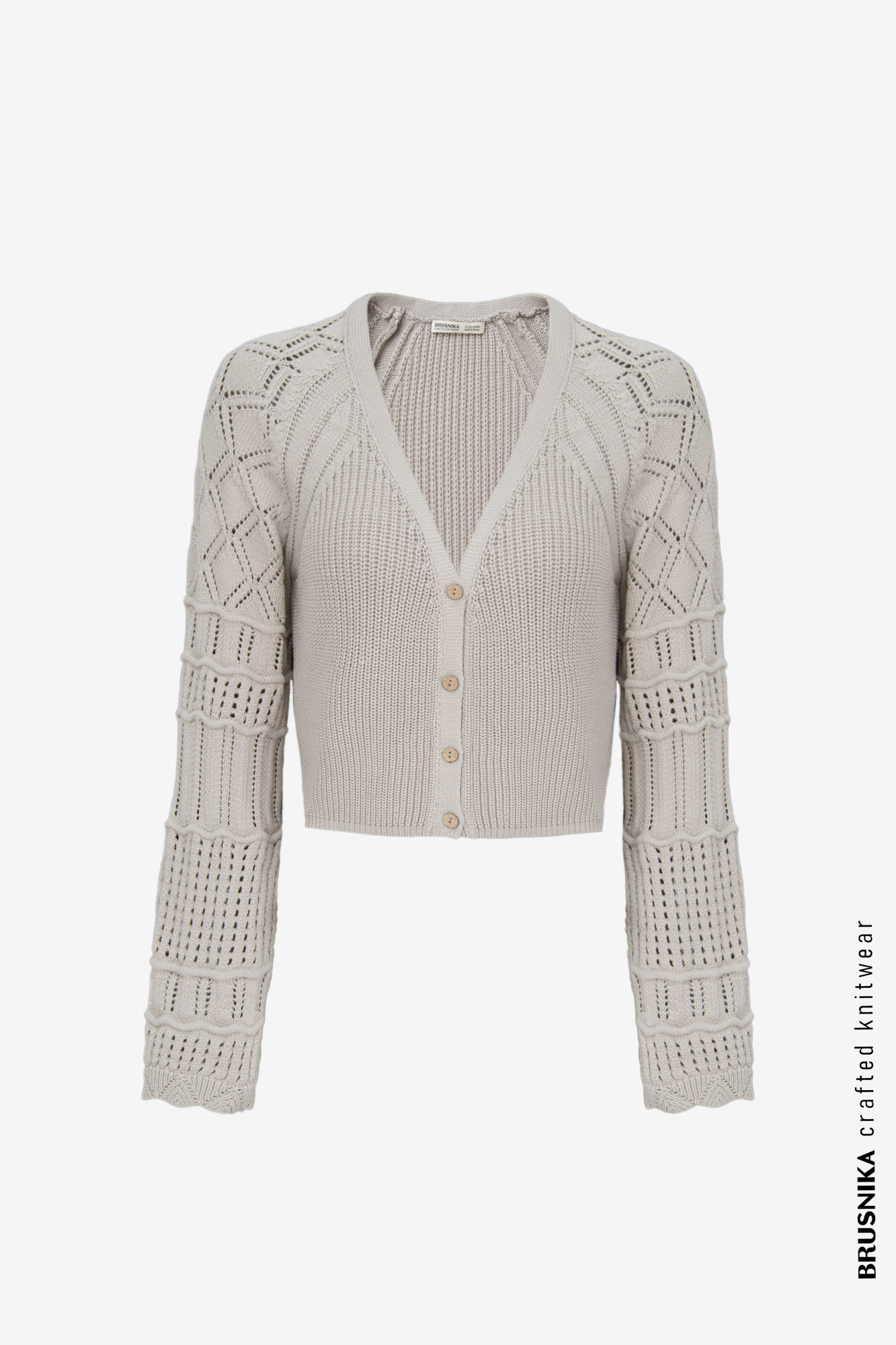 Трикотажный кардиган из хлопка с добавлением эластана. Модель укороченного кроя, с длинными вывязанными рукавами и застежкой на пуговицы.