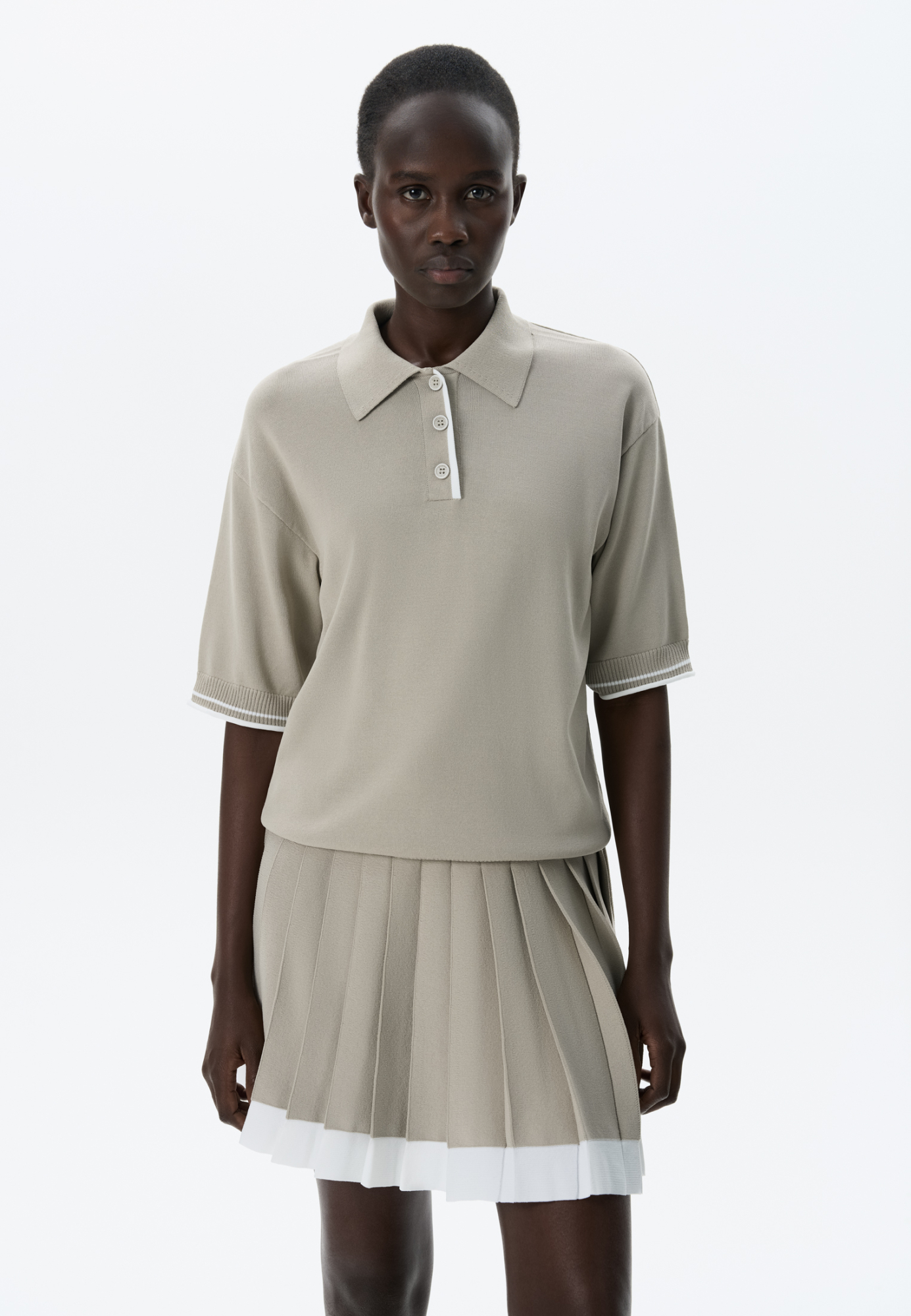 Трикотажная футболка поло из вискозы. Модель прямого силуэта, со спущенной линией плеч, короткими рукавами, отложным воротником-поло и планкой с тремя пуговицами. Рукава и нижний край изделия декорированы кантом контрастного цвета.