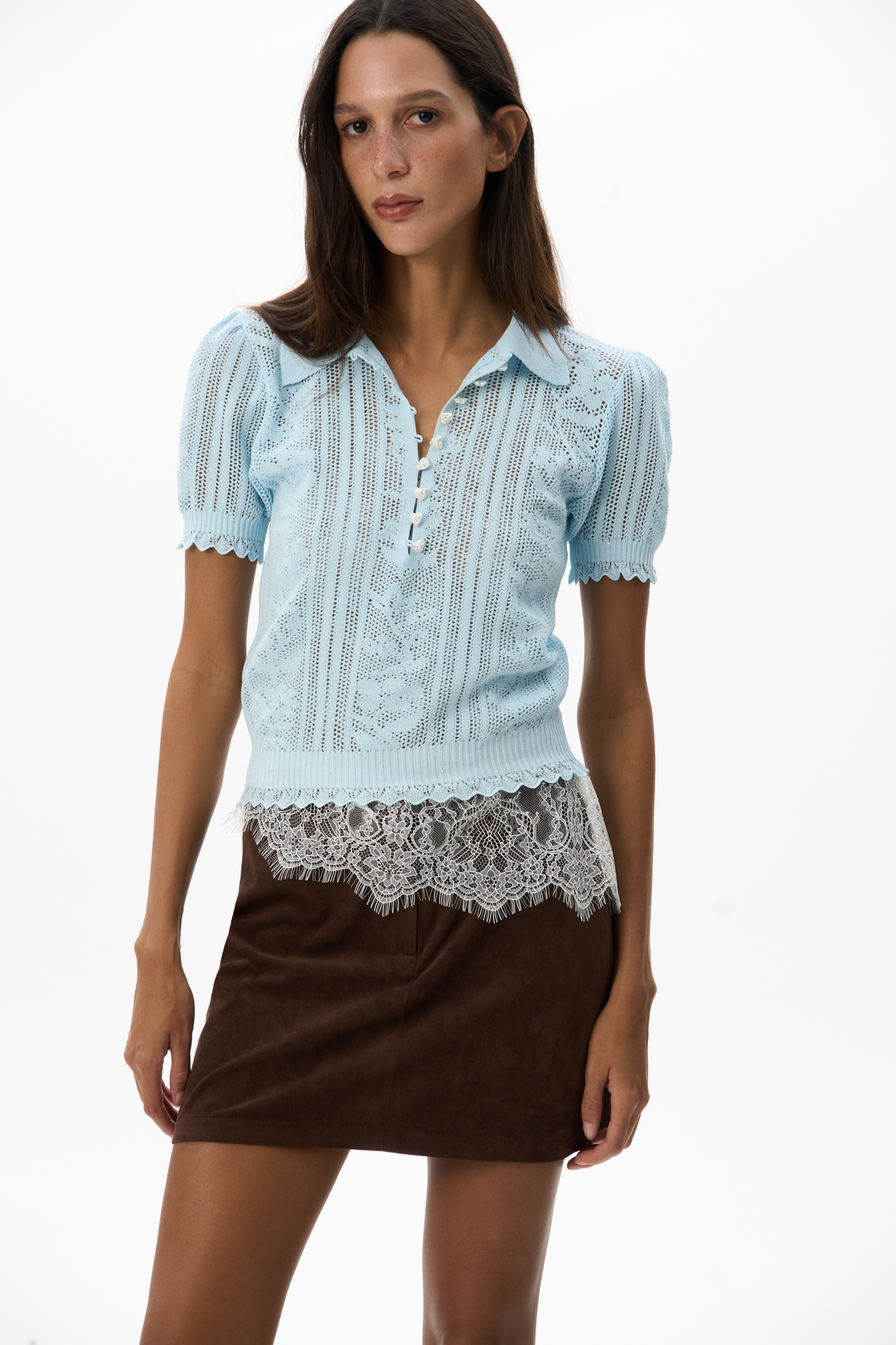 Трикотажная футболка из вискозы с пайетками. Изделие выполнено ажурным переплетением с дизайном в виде растительного орнамента. Модель с воротником поло, планкой на пуговицах-сердечках и коротким рукавом.