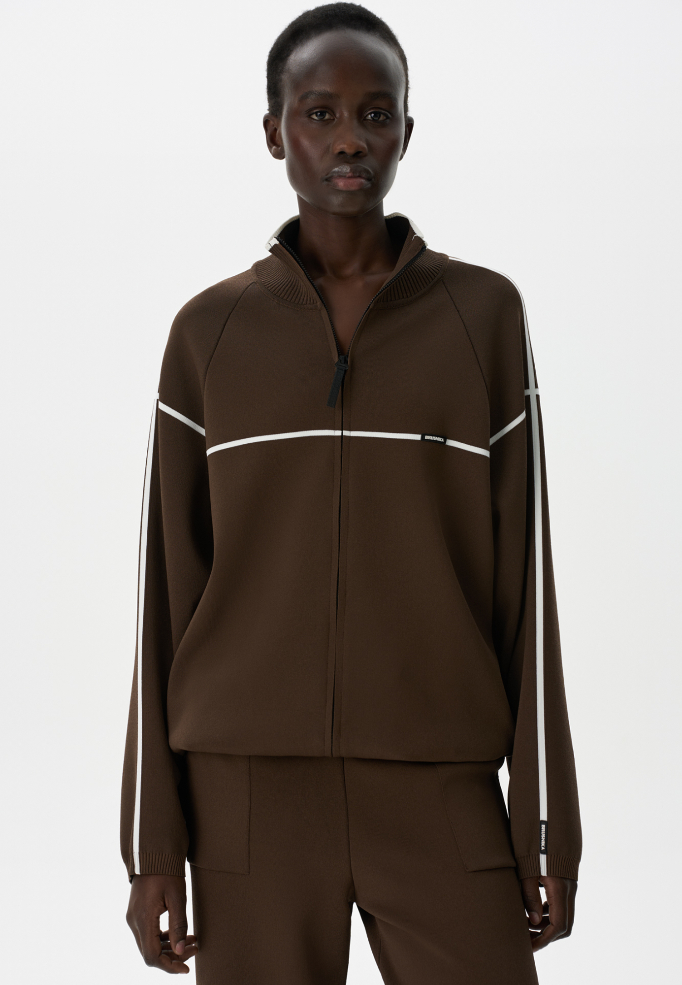 Вискозный трикотажный бомбер спортивного стиля с контрастными лампасами. Модель прямого кроя с длинными рукавами, манжетами на эластичной резинке и воротником-стойкой. По низу изделия предусмотрена регулируемая кулиска. Застежка на молнию.