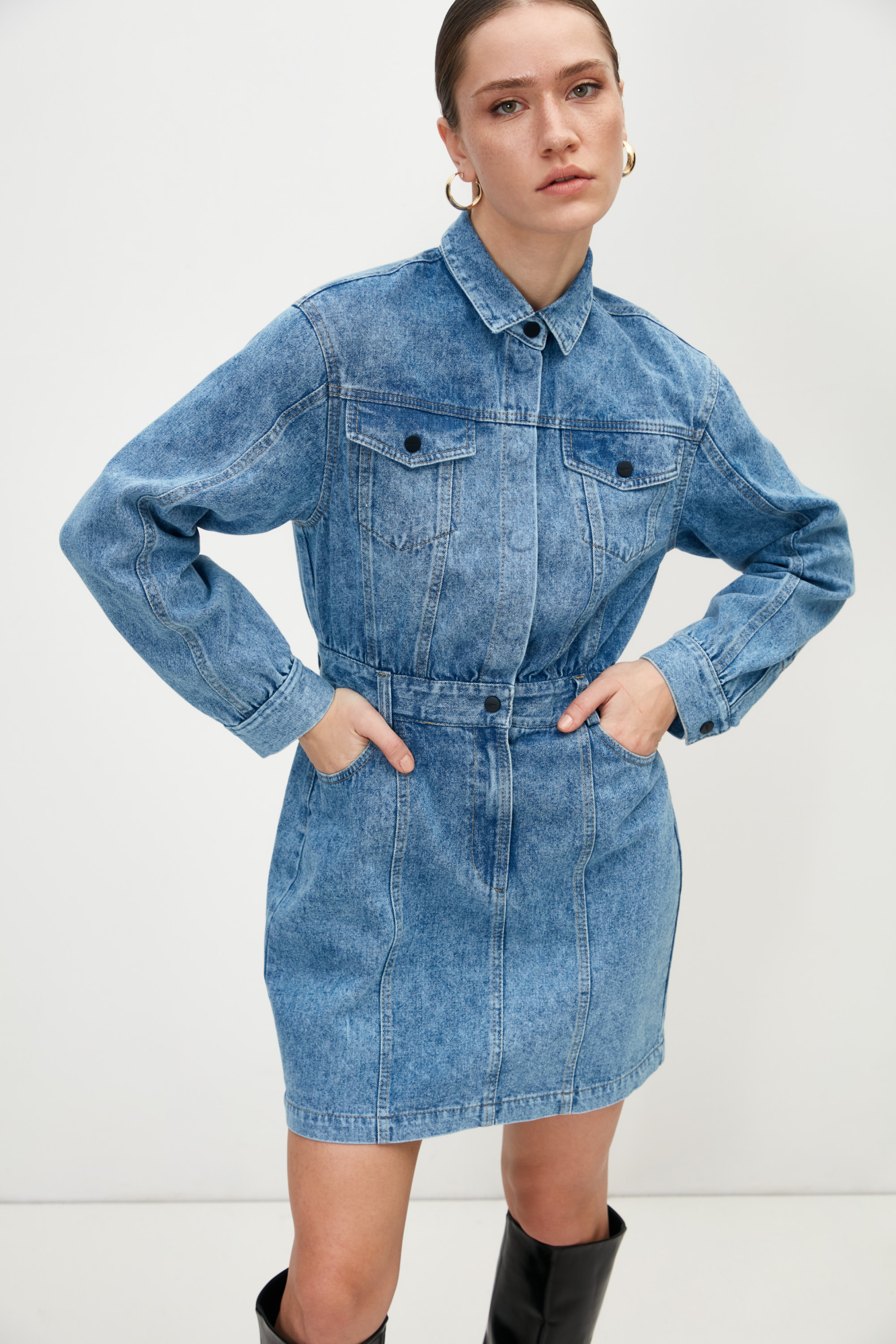 Джинсовое платье длины мини из 100% хлопка. Модель приталенного силуэта, с длинными рукавами, отложным воротником, нагрудными карманами с клапанами и боковыми карманами на поясе для ремня. Застежка на металлические кнопки.