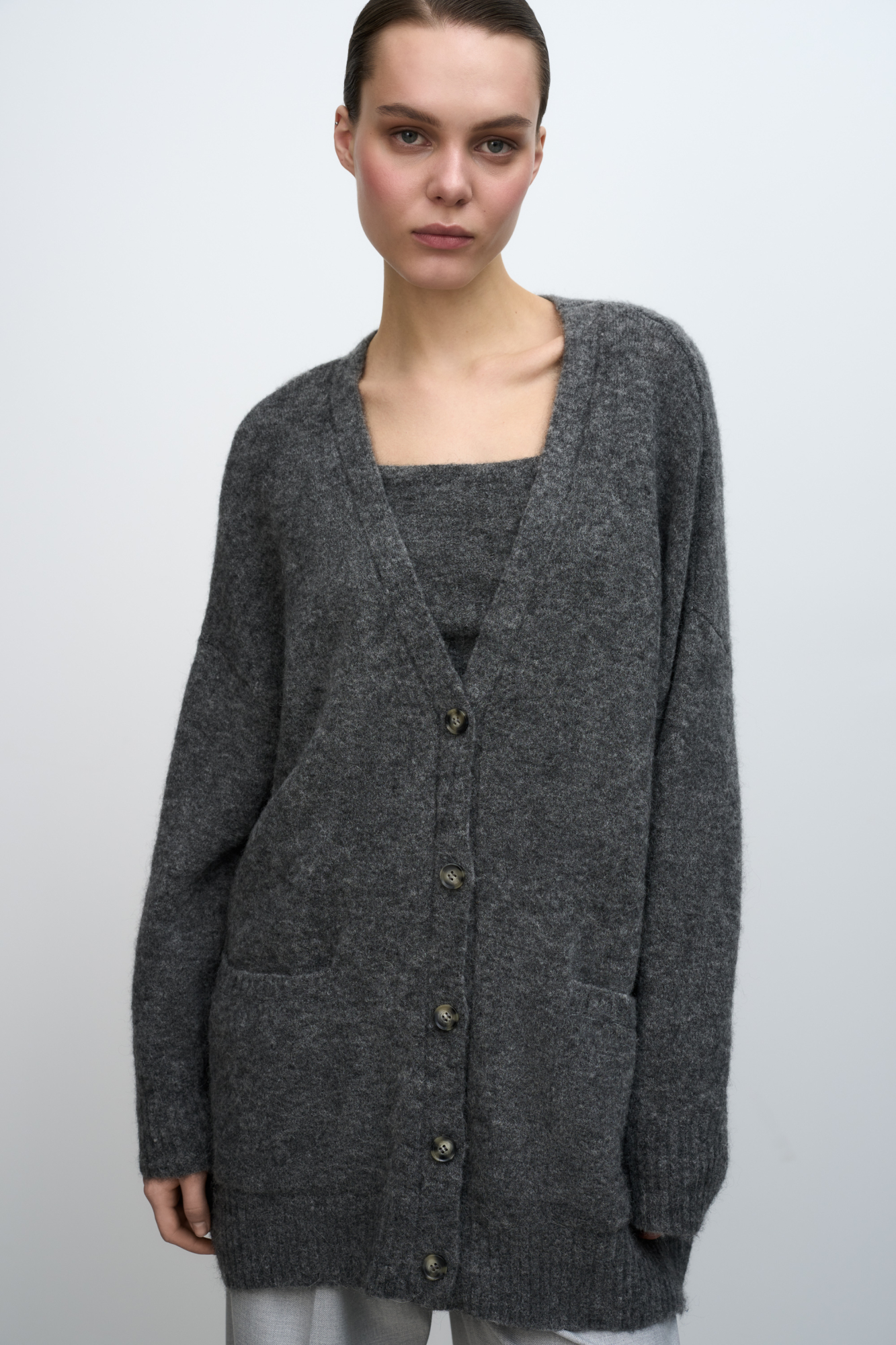 Трикотажный кардиган из шерсти альпака. Модель свободного силуэта со спущенной линией плеча, манжеты рукавов на резинке. 2 накладных кармана. Застежка на пуговицы.