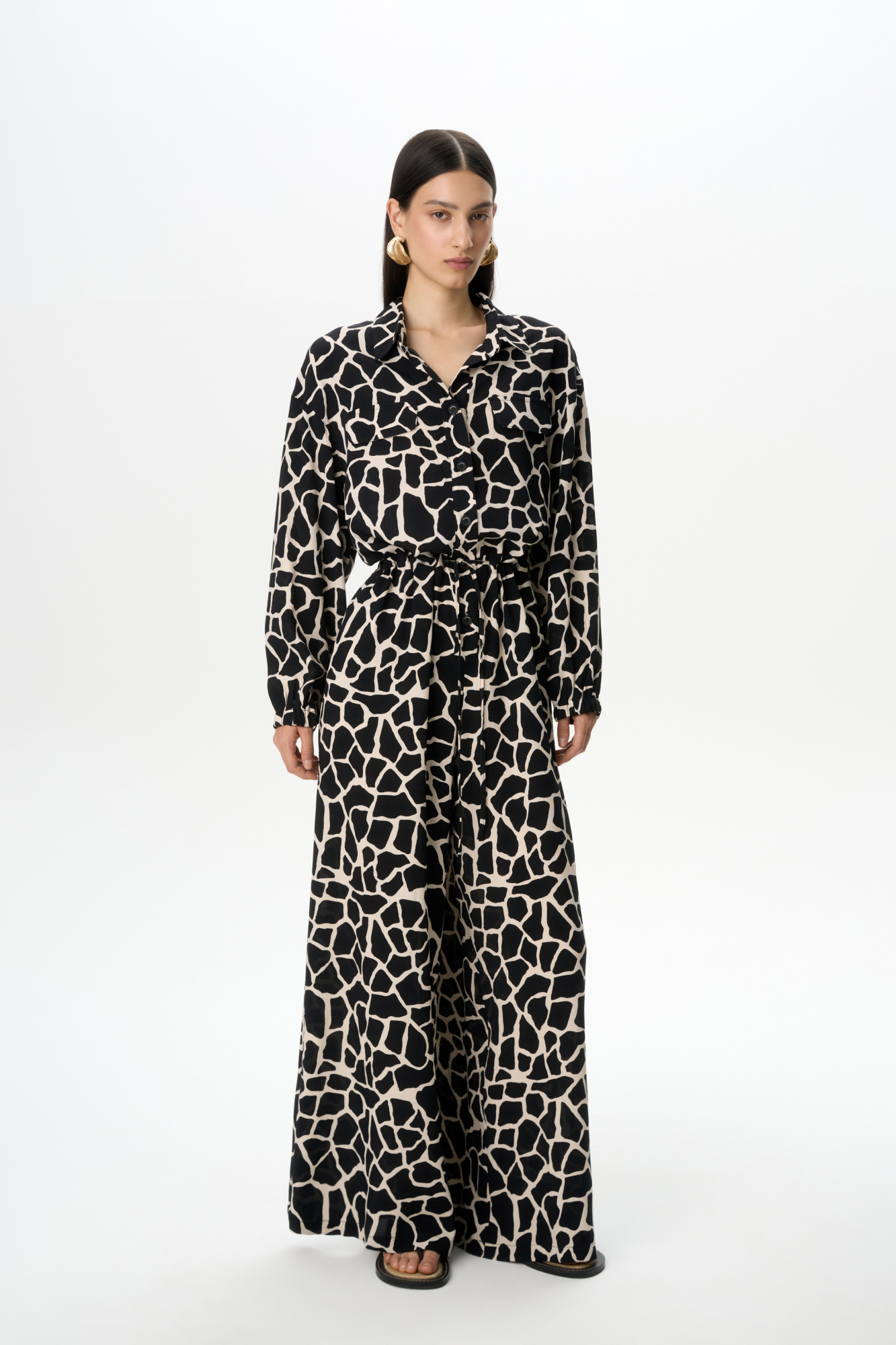 Принтованный комбинезон из 100% вискозы с поясом и застежкой на пуговицы. 