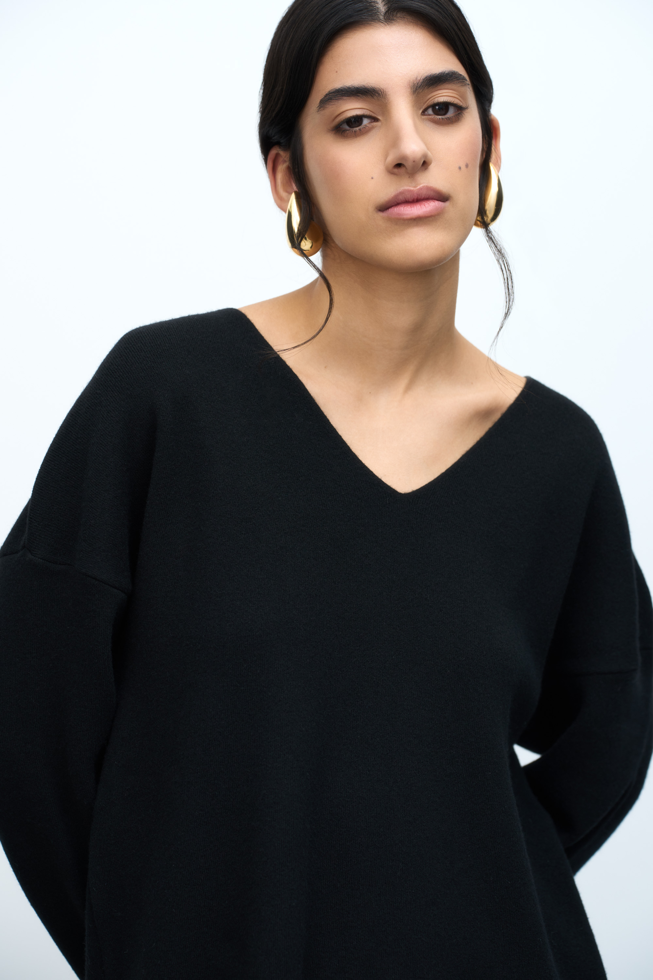 Удлиненный трикотажный джемпер из шерсти с добавлением кашемира. Модель свободного силуэта со спущенной линией плеча и глубоким V-образным вырезом. Дополнить образ можно комплектной юбкой.