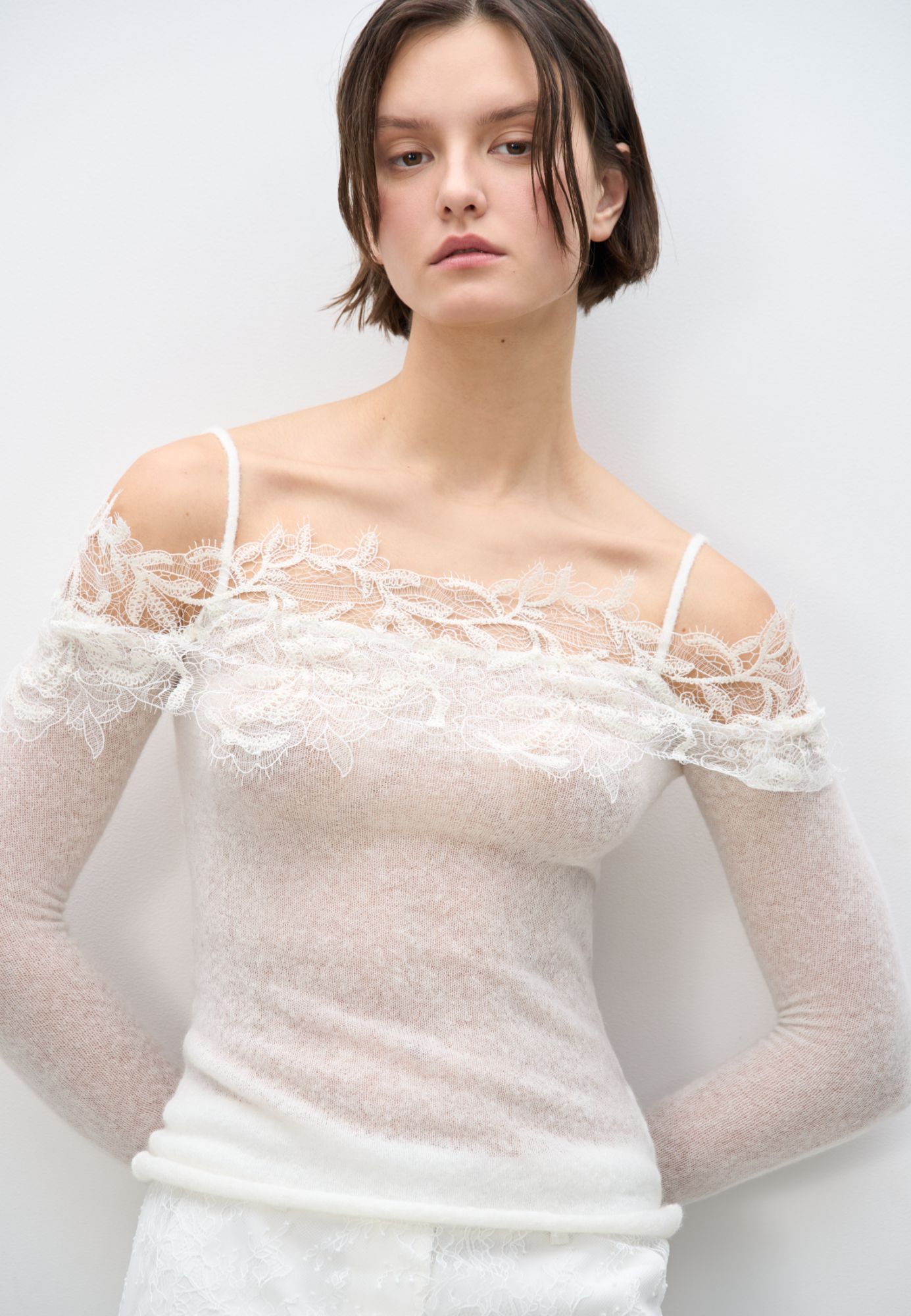 Трикотажный лонгслив из шерсти мериноса экстрафайн и альпака суперфайн. Модель по фигуре на тонких бретелях с длинными рукавами и открытой линией плеч. Декольте декорировано кружевом.
